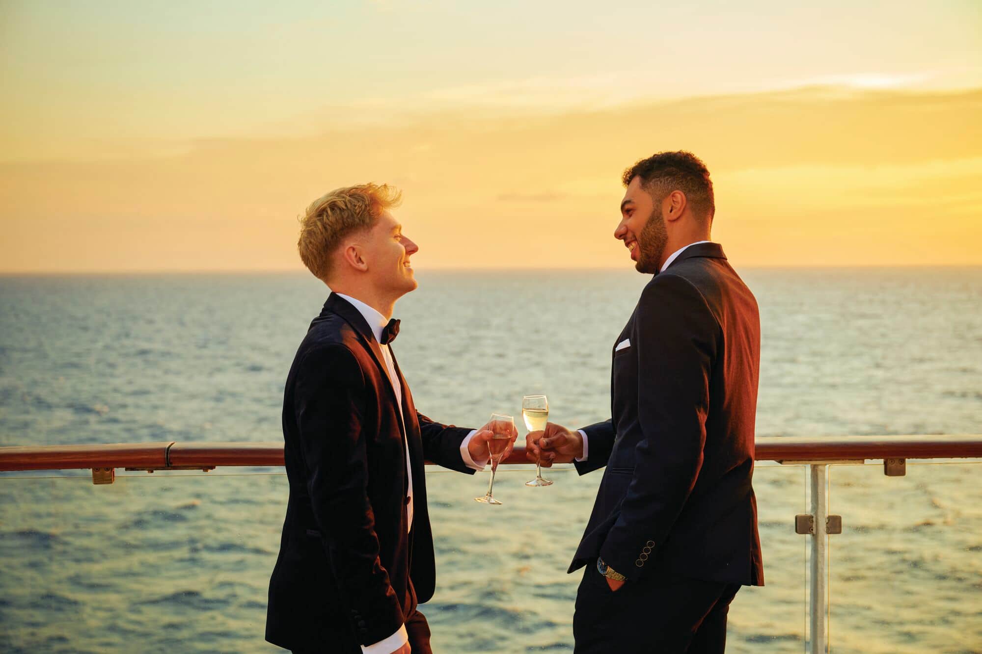 Owen and Josh wearing tuxedos and drinking wine on the deck of the ship.