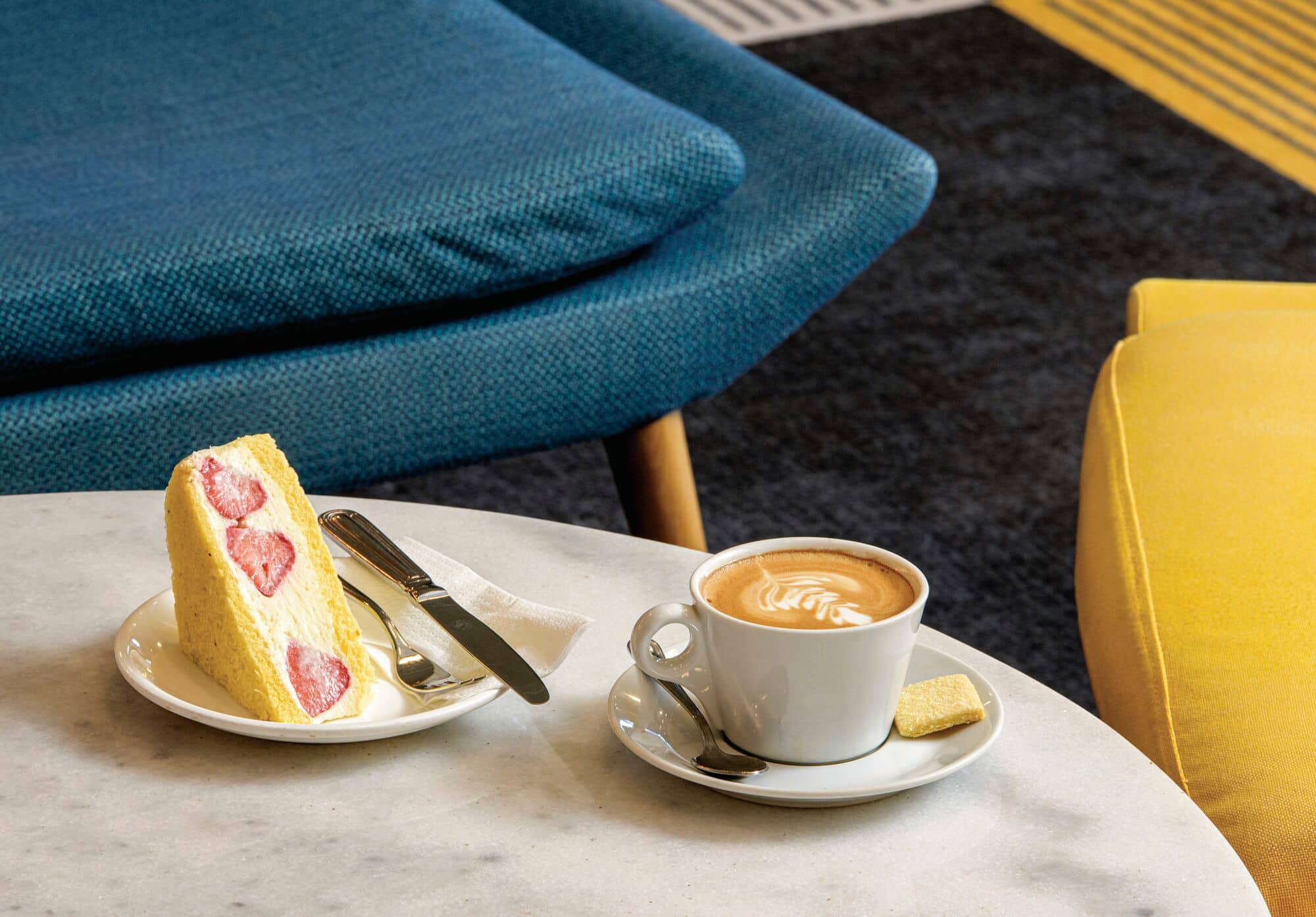 A coffee and cake laid out on a coffee shop table.