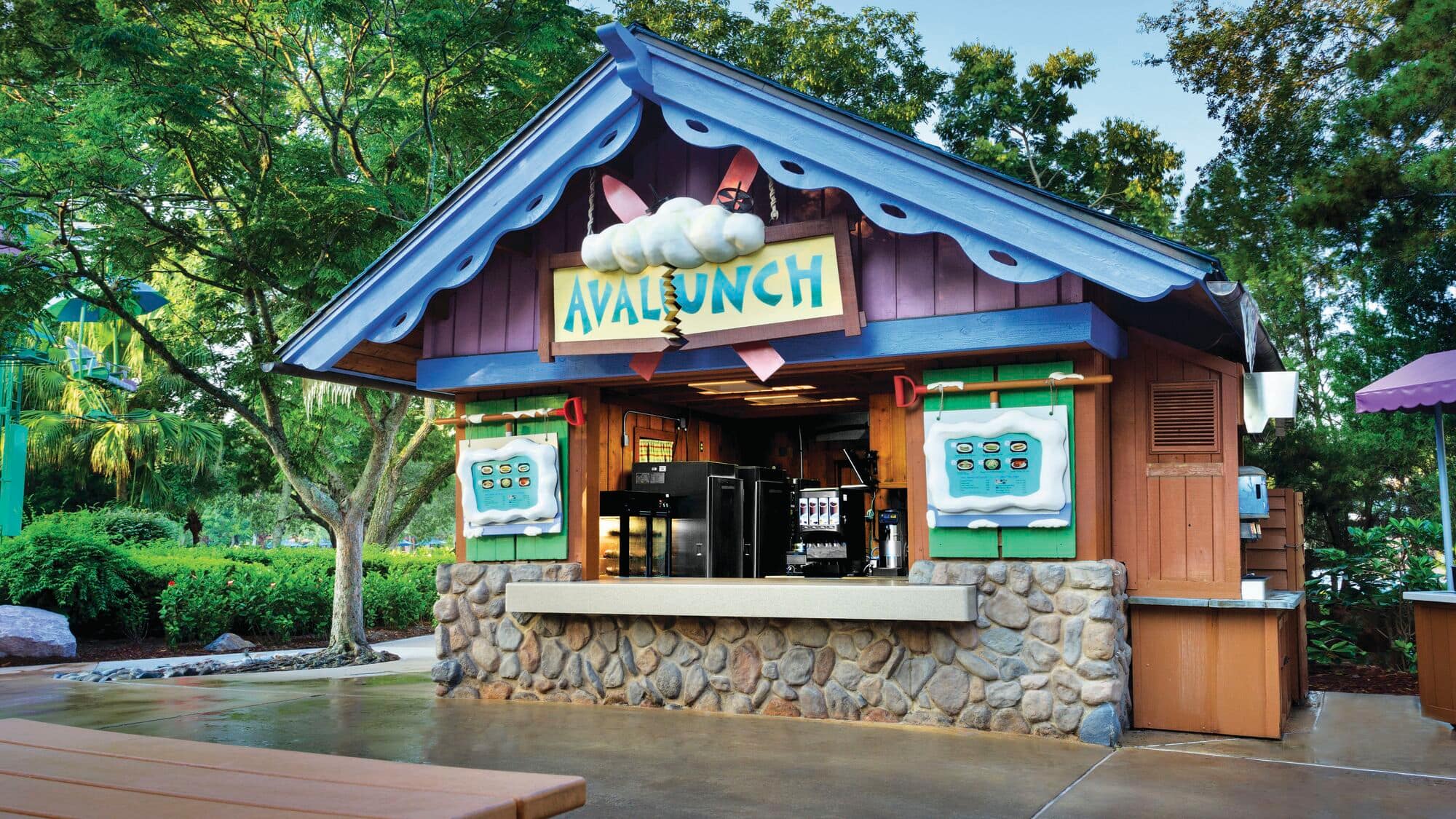 Avalunch is an outdoor food kiosk with a menu that lists hot dogs, snacks, and a selection of soft drinks and draft beer.