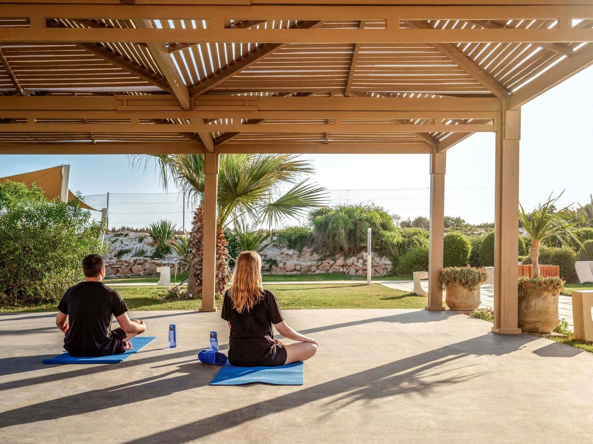 People doing yoga on mats in the sun.