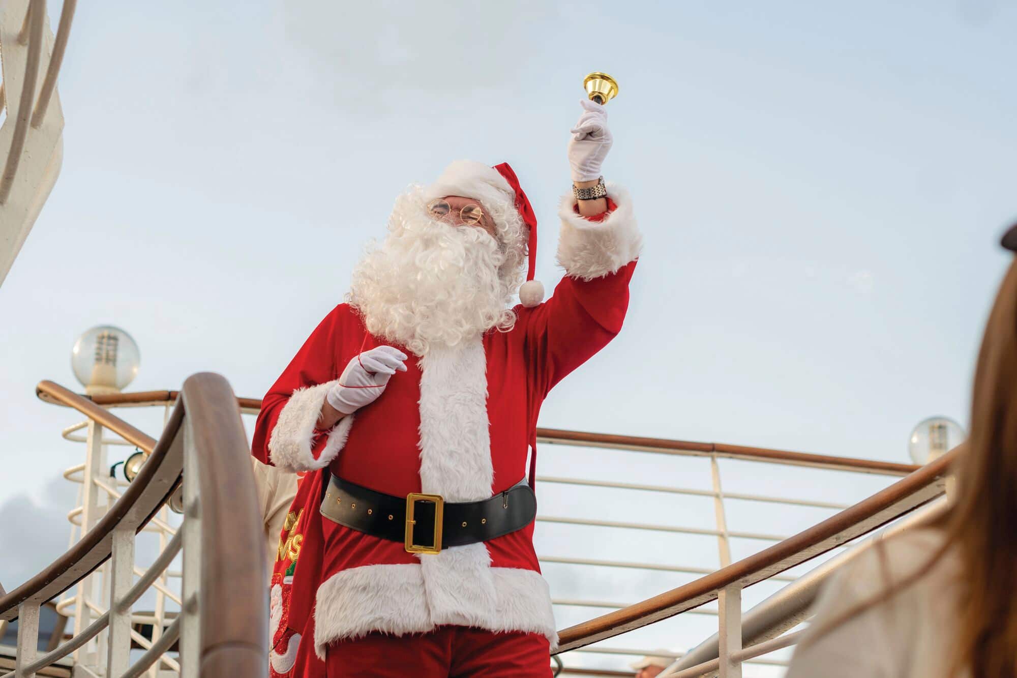 Santa ringing a bell on a cruise deck.