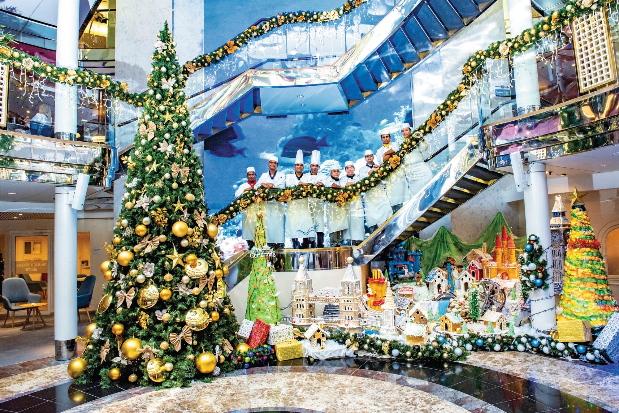 Cruise ship interior decorated for Christmas with chefs in a line on the staircase.