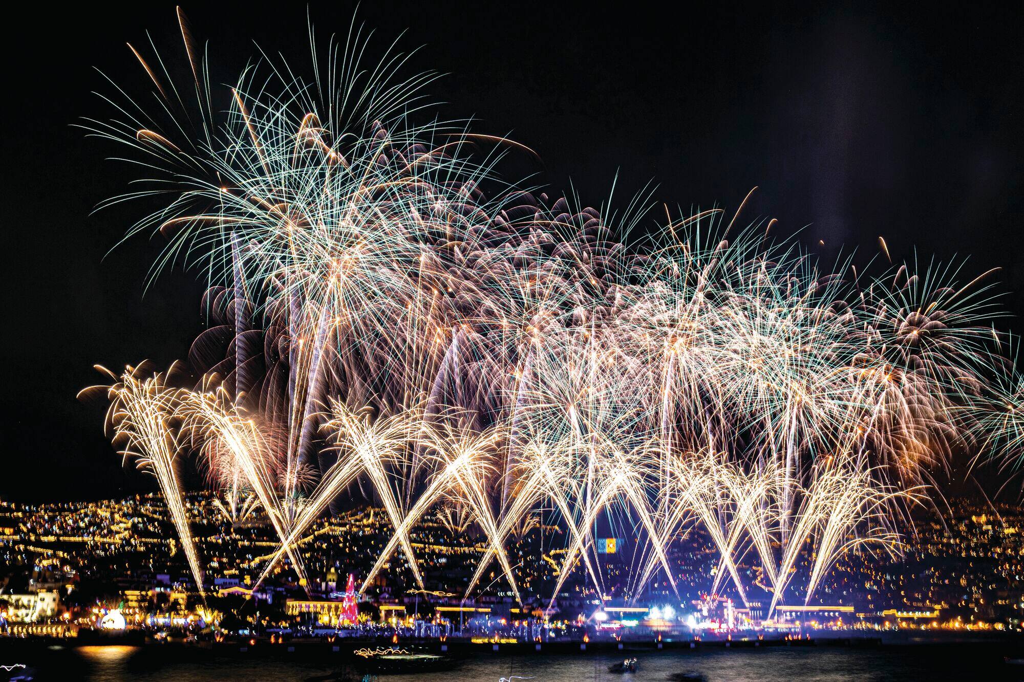 A big fireworks display above a river.