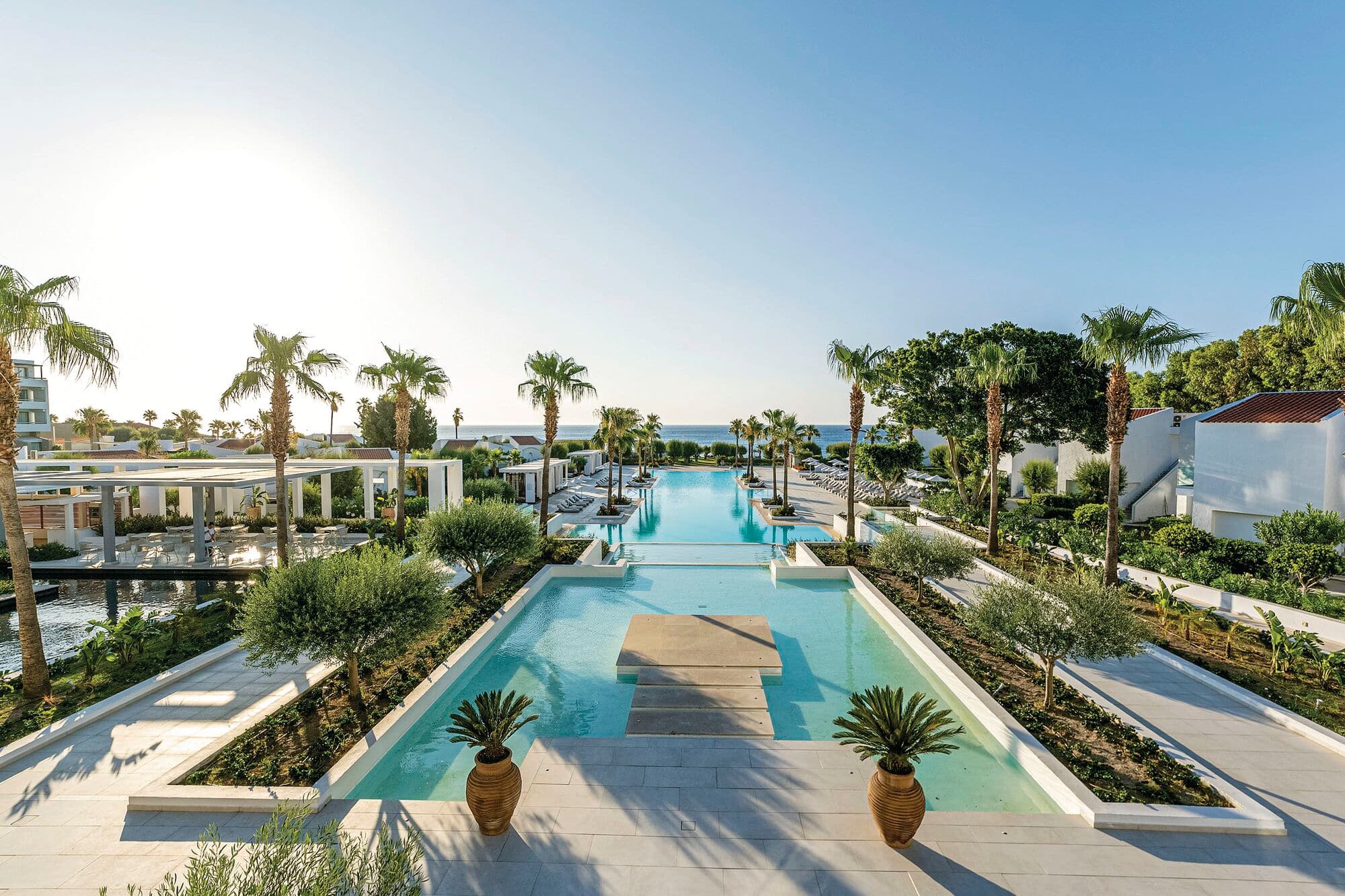 A hotel pool at Grecotel LUXME Dama Dama resort stretching out form the main building to the beach.
