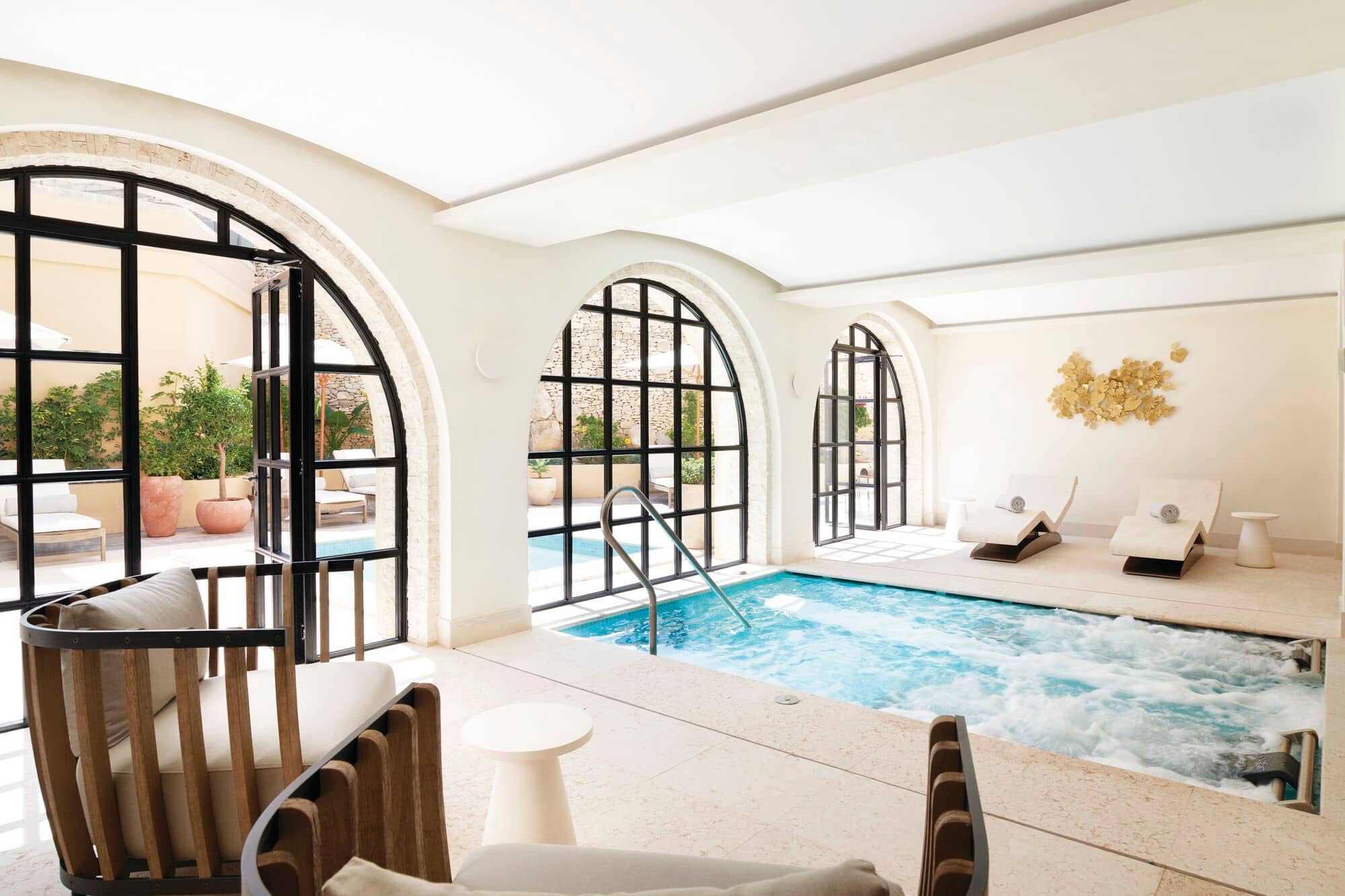 A bright indoor spa pool with loungers at The Corinthia Palace Malta.
