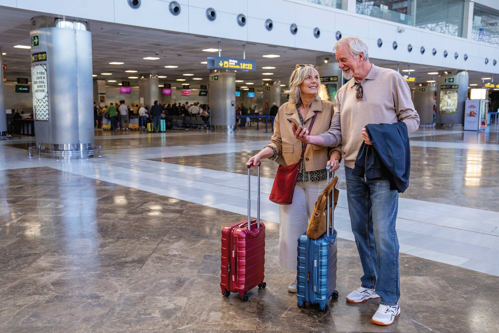 A couple walking through the airport with their luggage. 