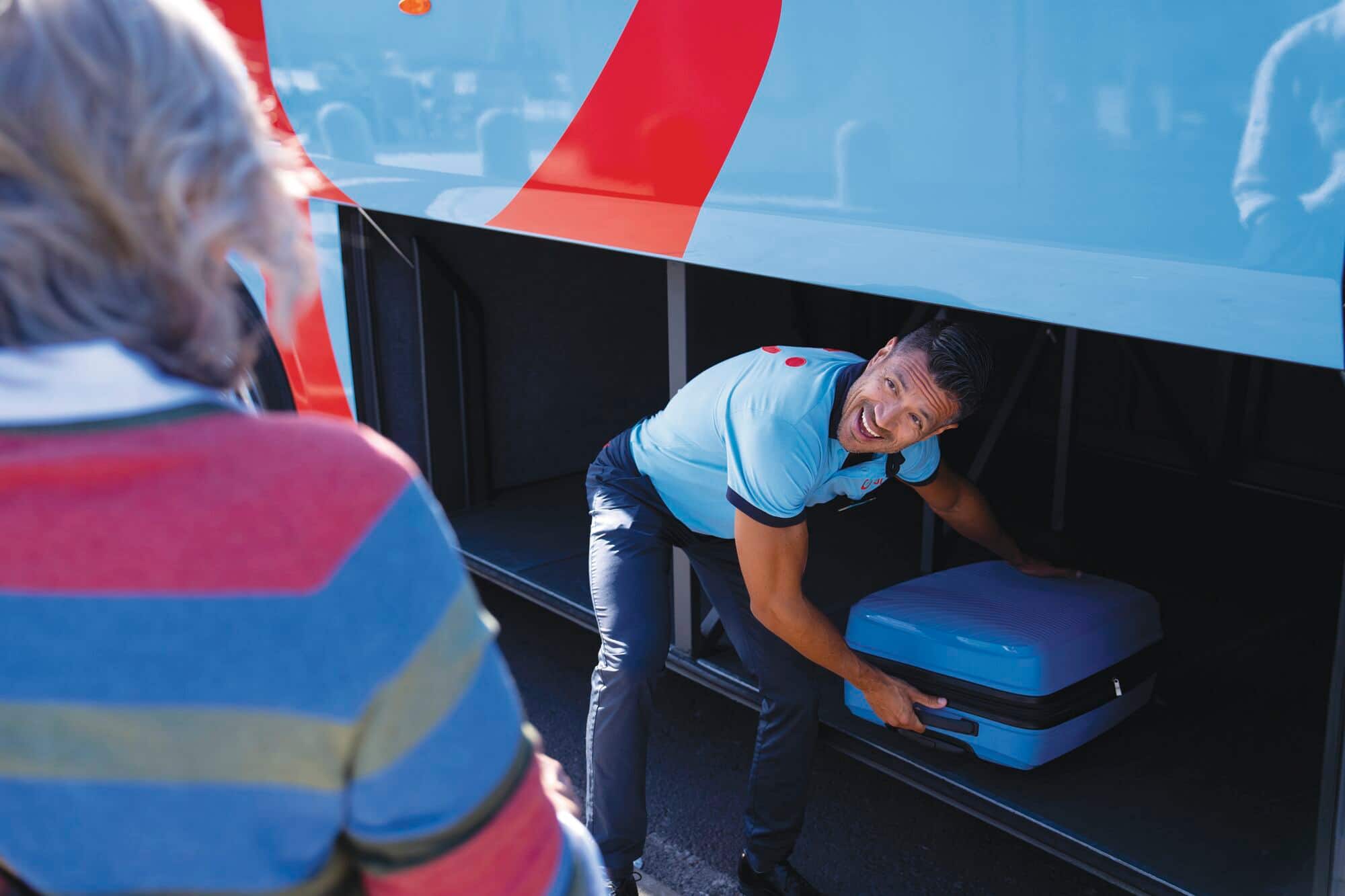 A TUI rep helping a customer to put their luggage in the coach hold. 
