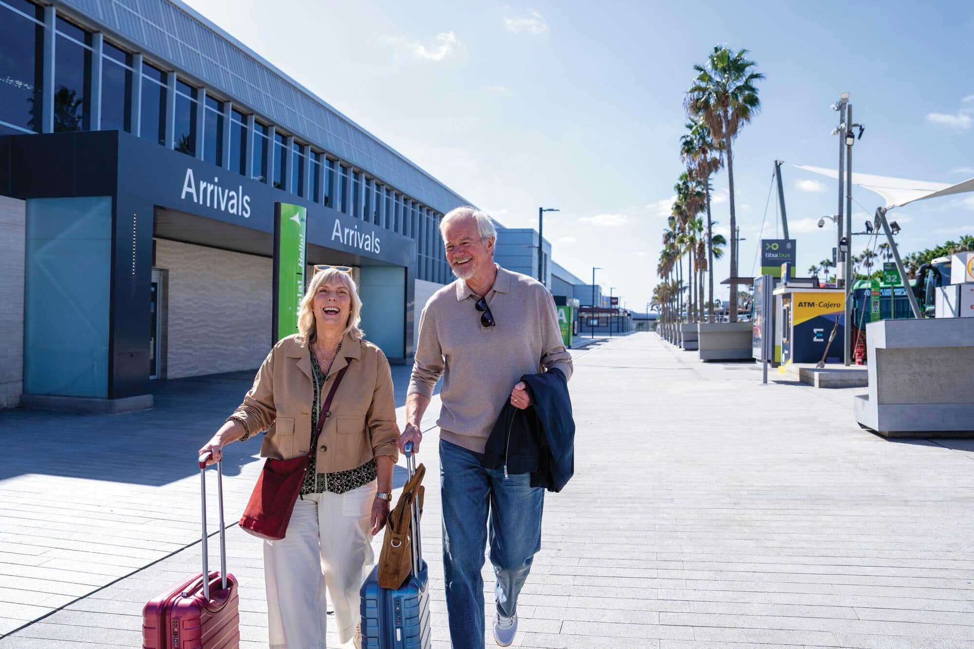 A couple outside arrivals with their luggage.