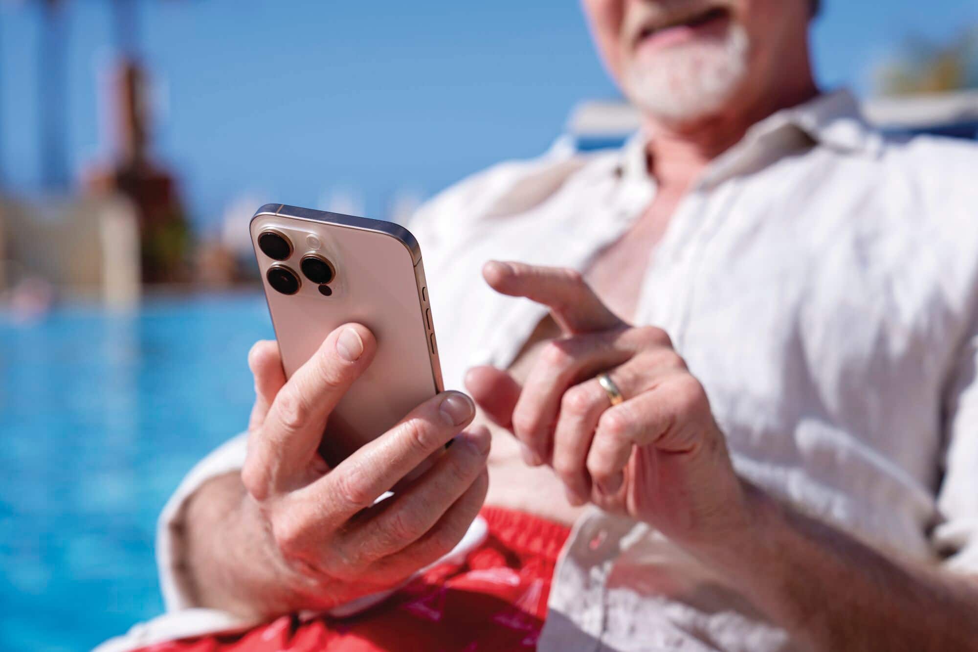 Man on a sunlounger holding an iPhone.