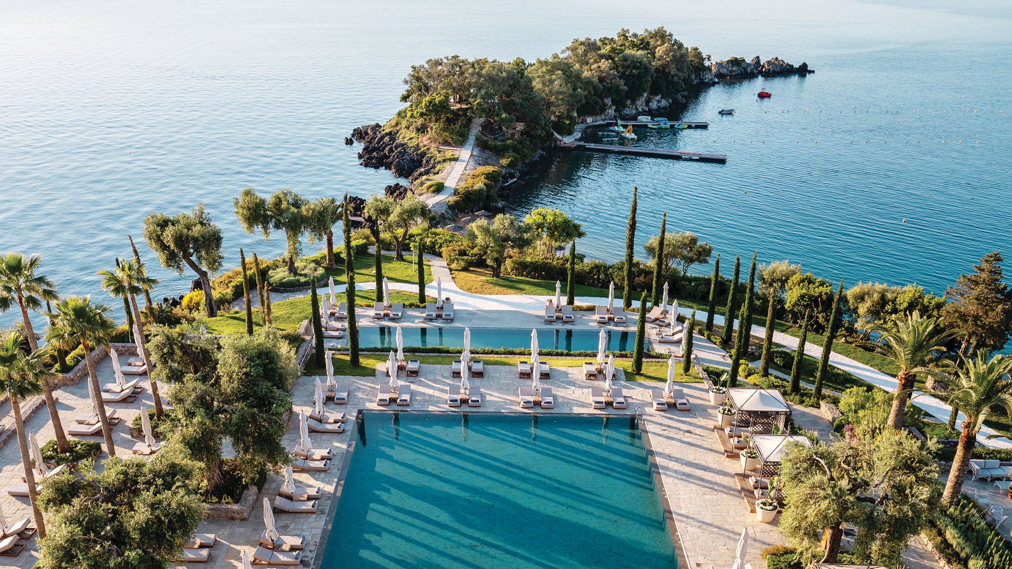 Overhead view of a hotel pool and surrounding sea.