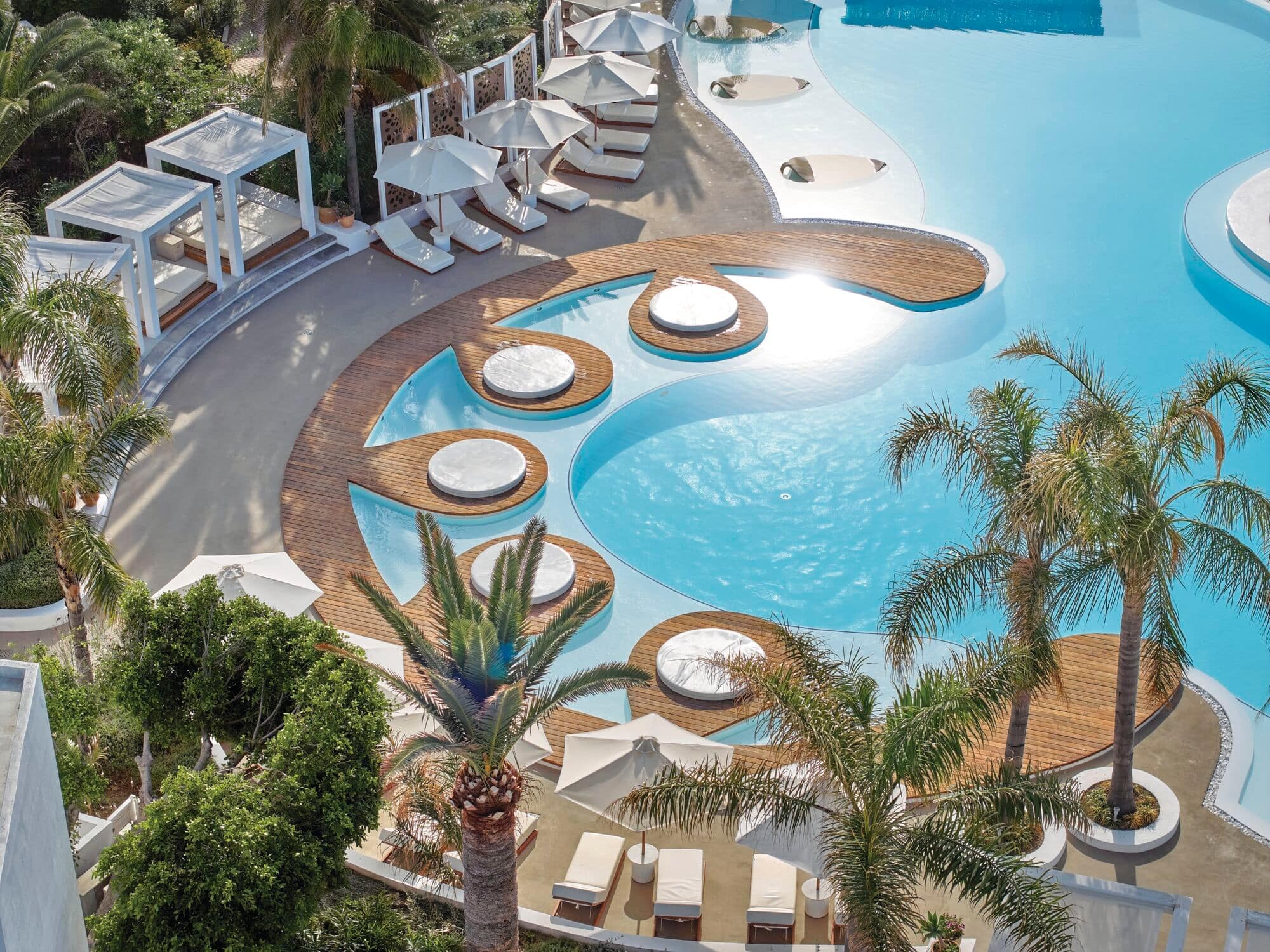 A curvy hotel swimming pool with smart wooden decking.