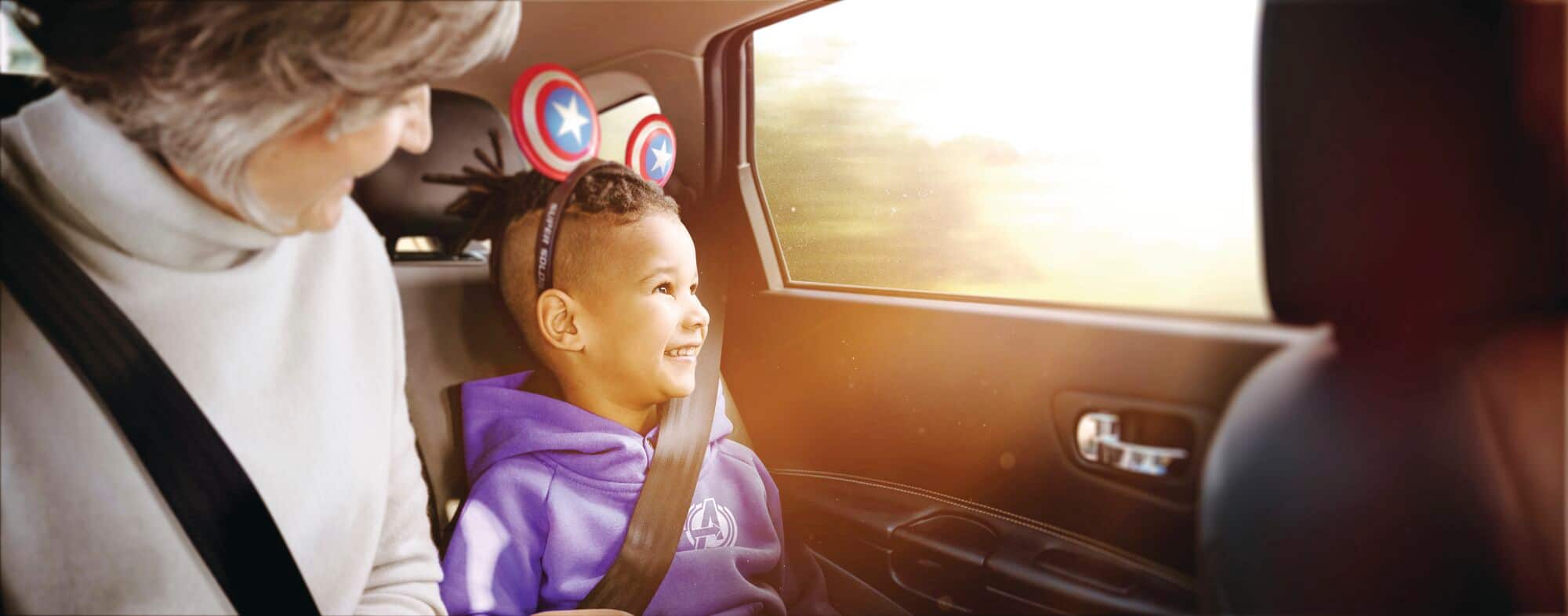 A child wearing Captain America themed Mickey Ears in a car.