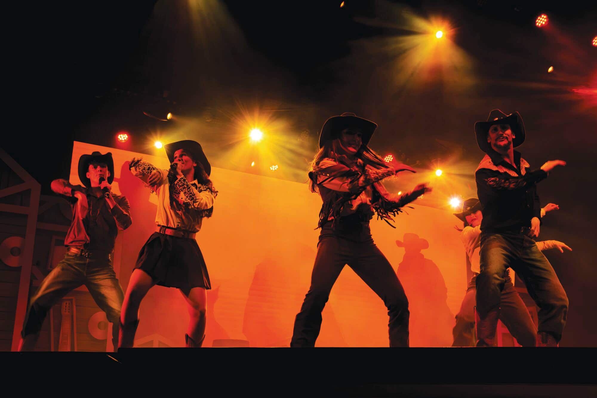 5 people line dancing on stage.