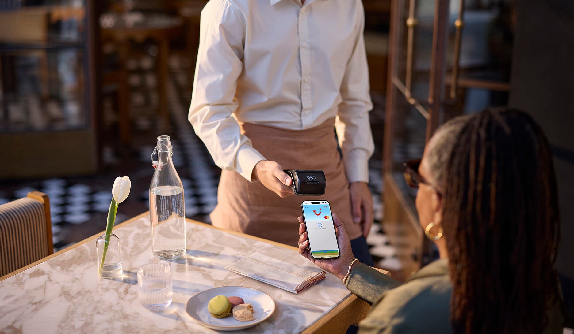 A woman using Apple Pay on her phone to pay at a restaurant.