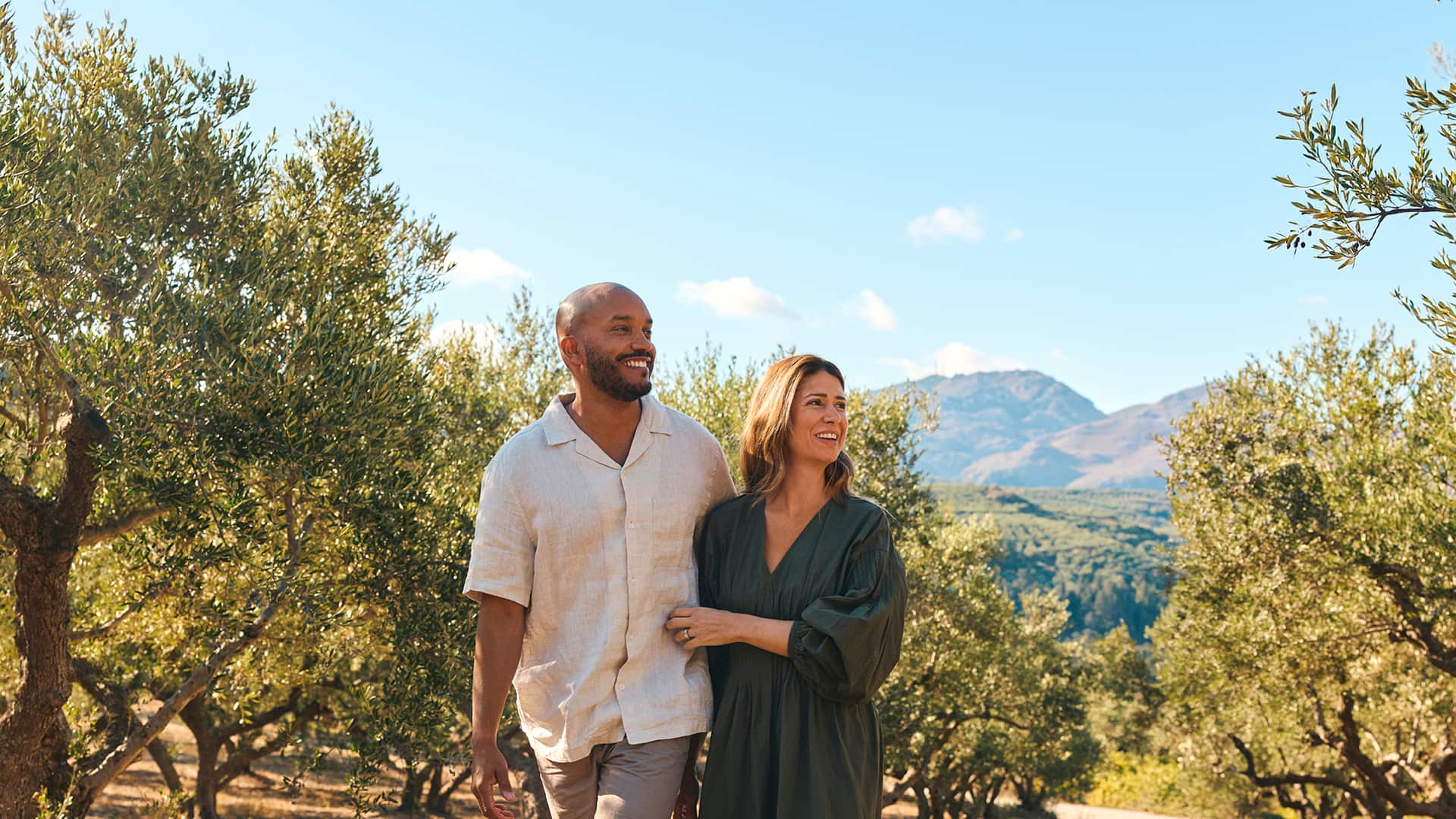 A couple walking in the countryside, with mountains in the background.