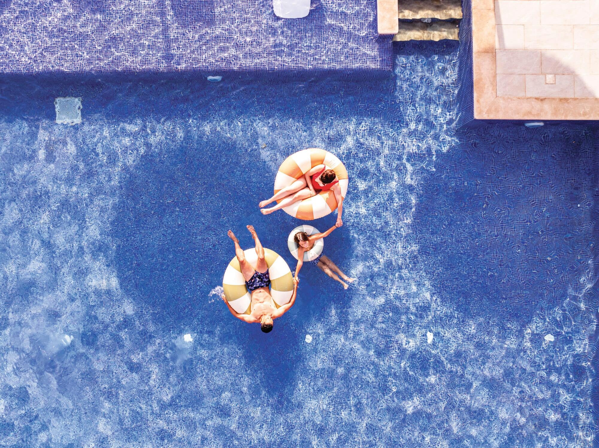 A topdown view of a family relaxing in inflatable pool rings.