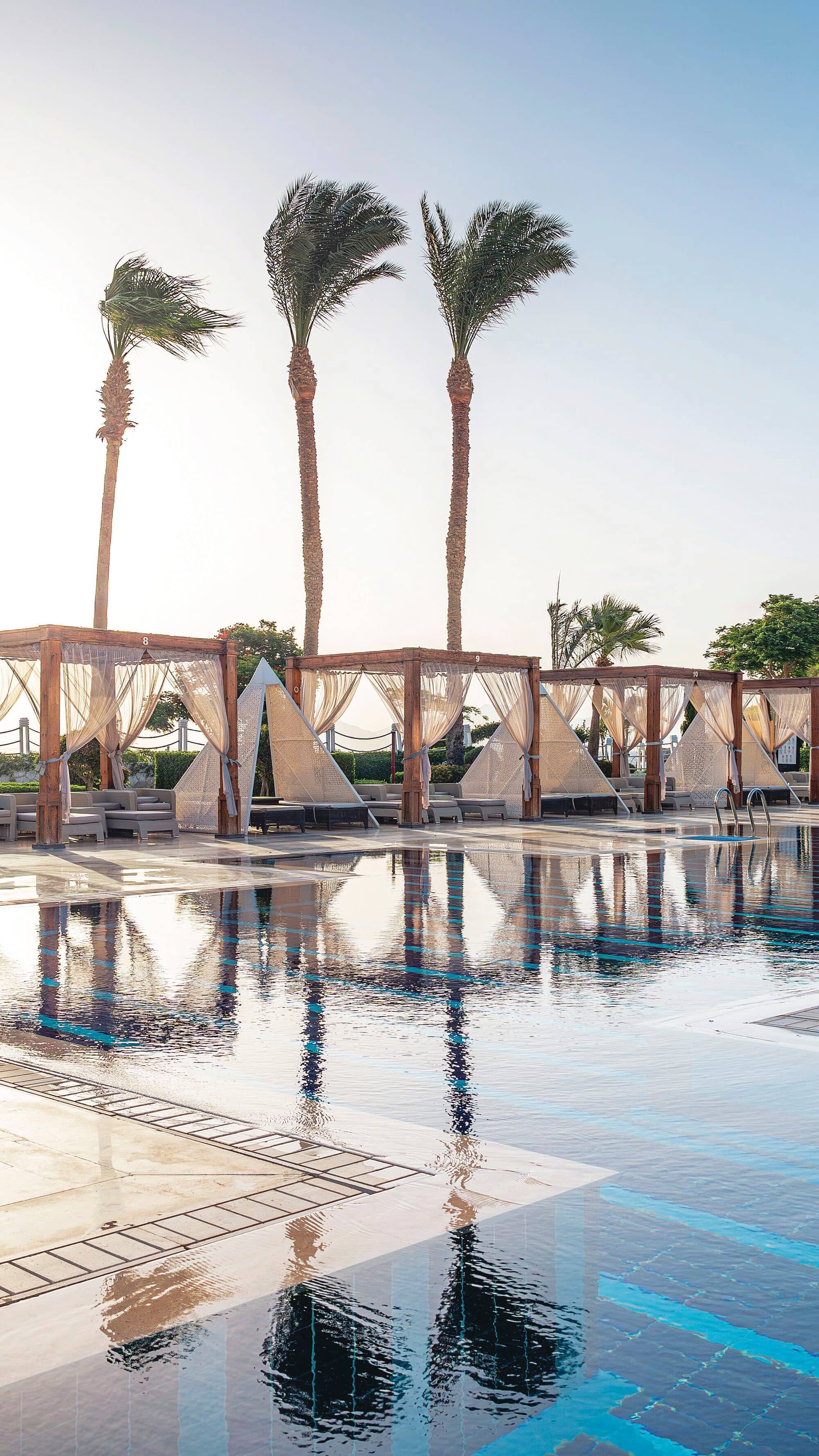 A pool lined with private cabanas.