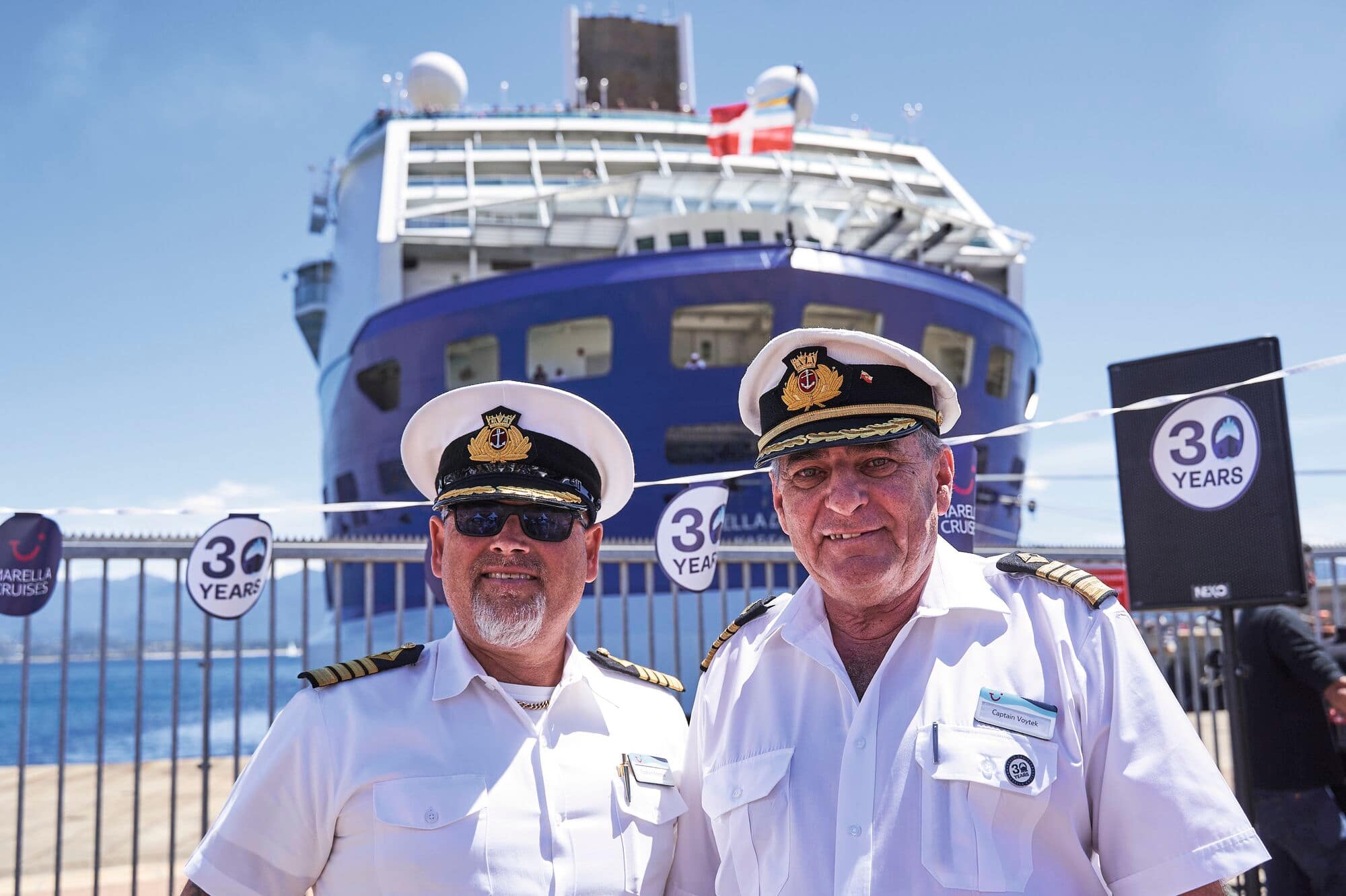Two captains in front of a Marella ship.