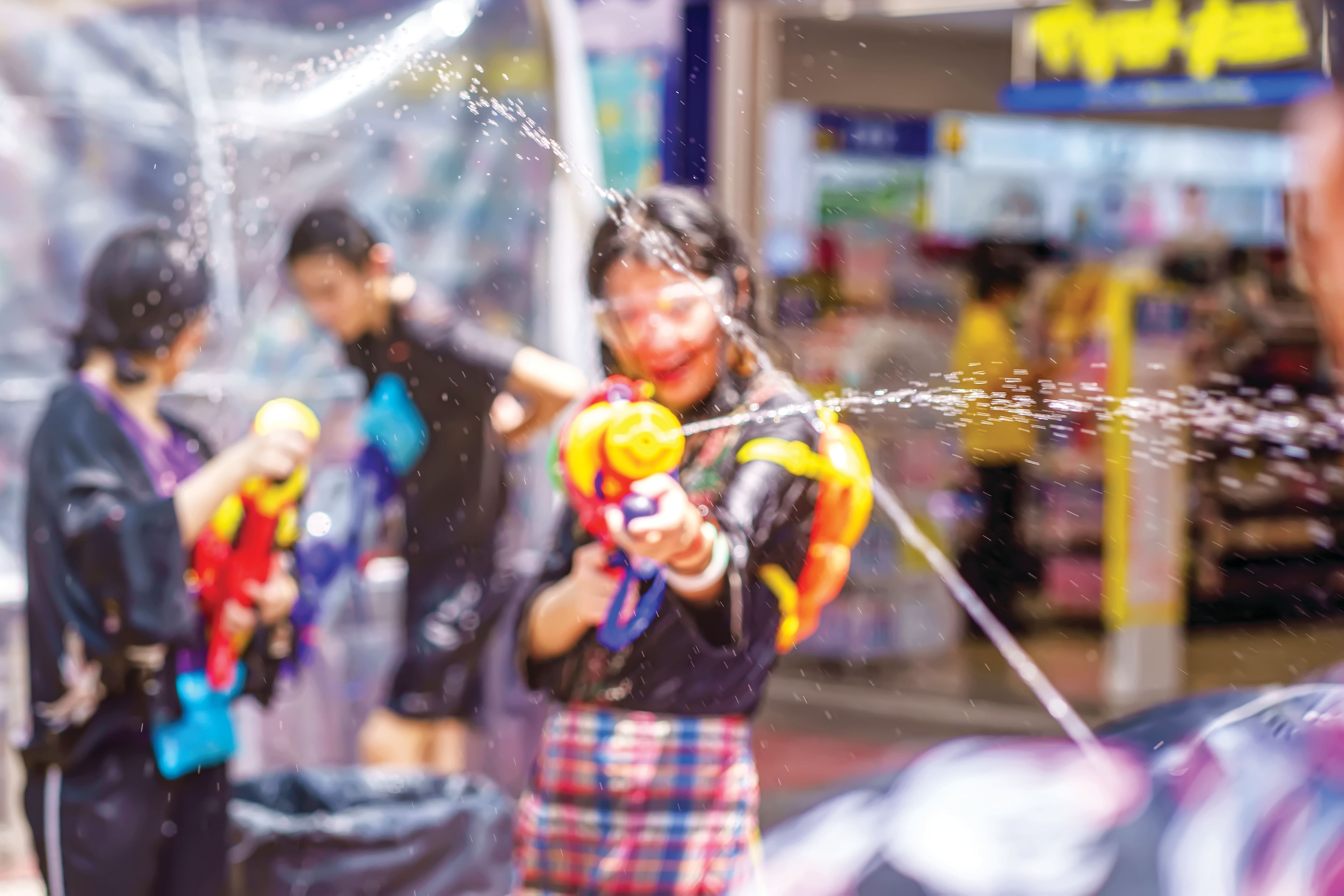 People spraying water at each other during a street festival.