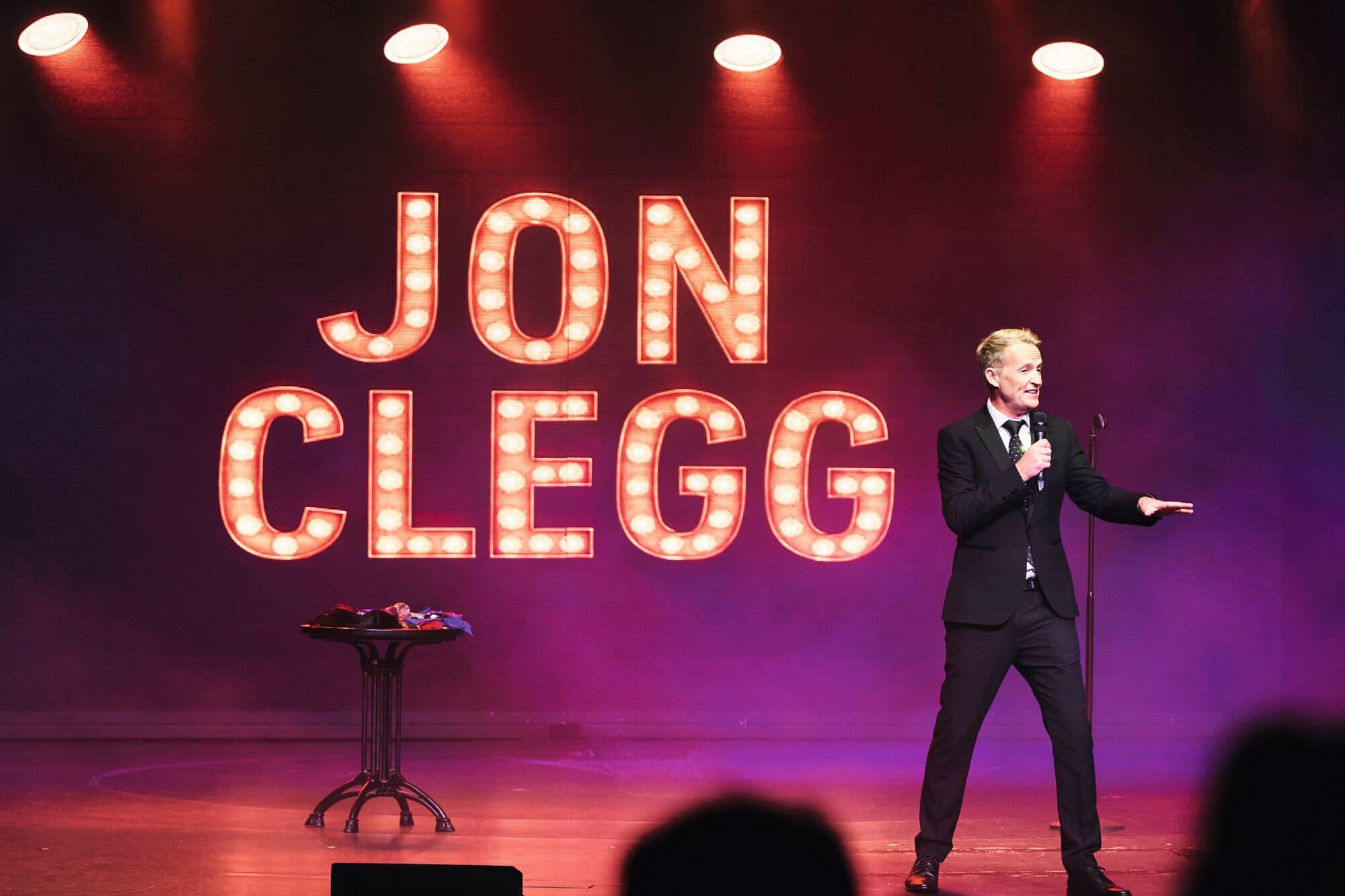 Comedian Jon Clegg performing on stage.