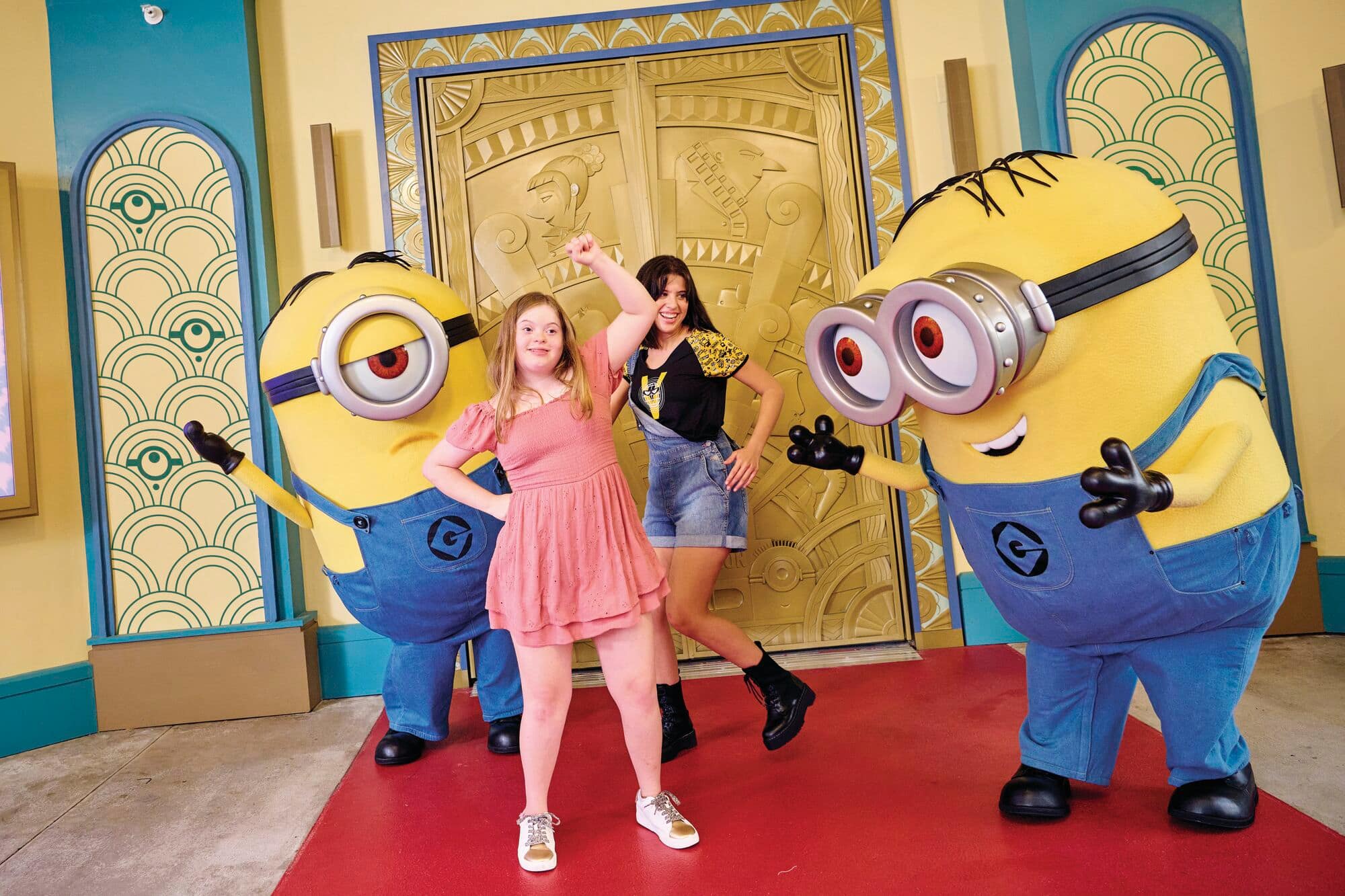 Two young girls posing with a pair of minions. 