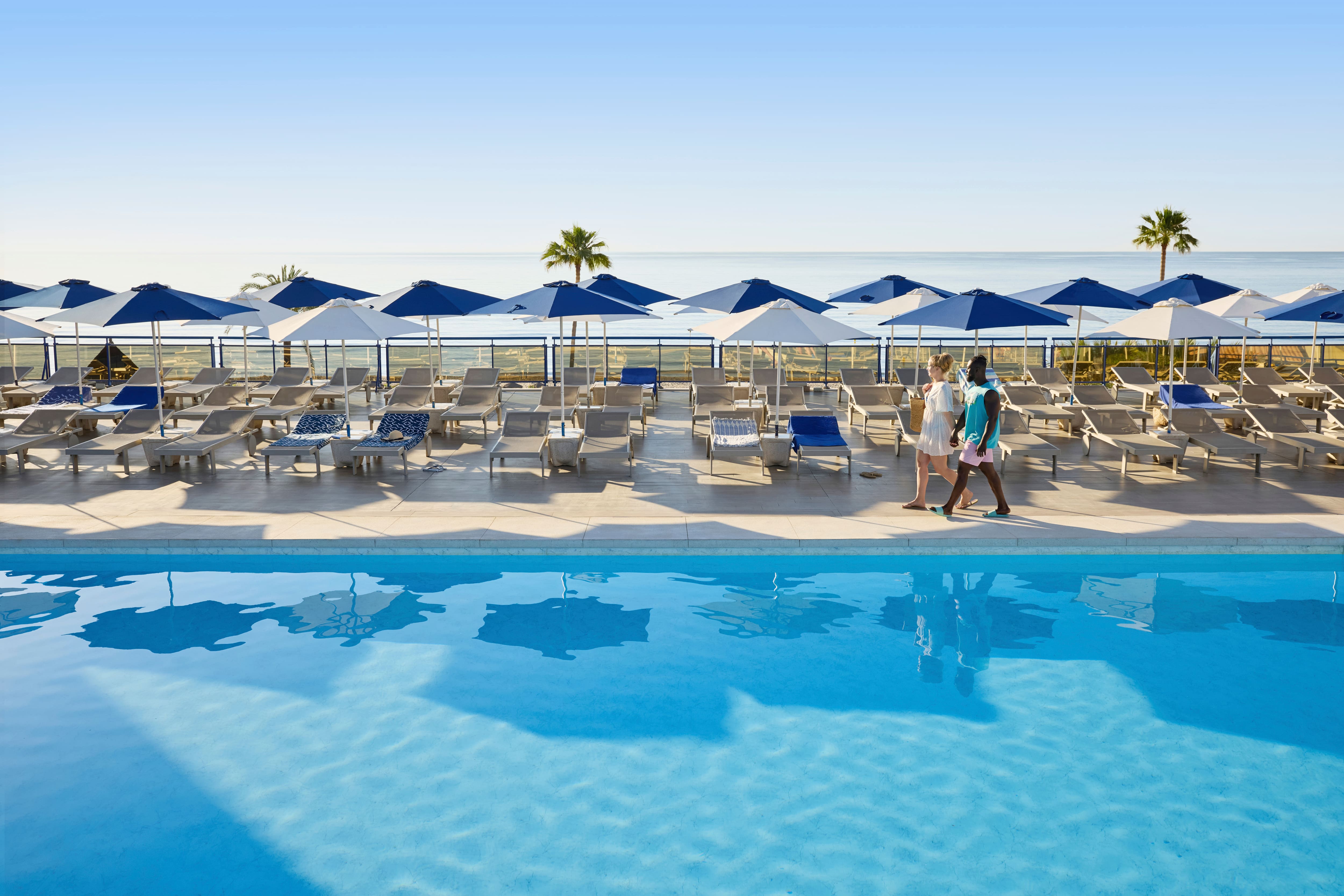 A couple walking past the seafront pool at TUI BLUE Yaramar.