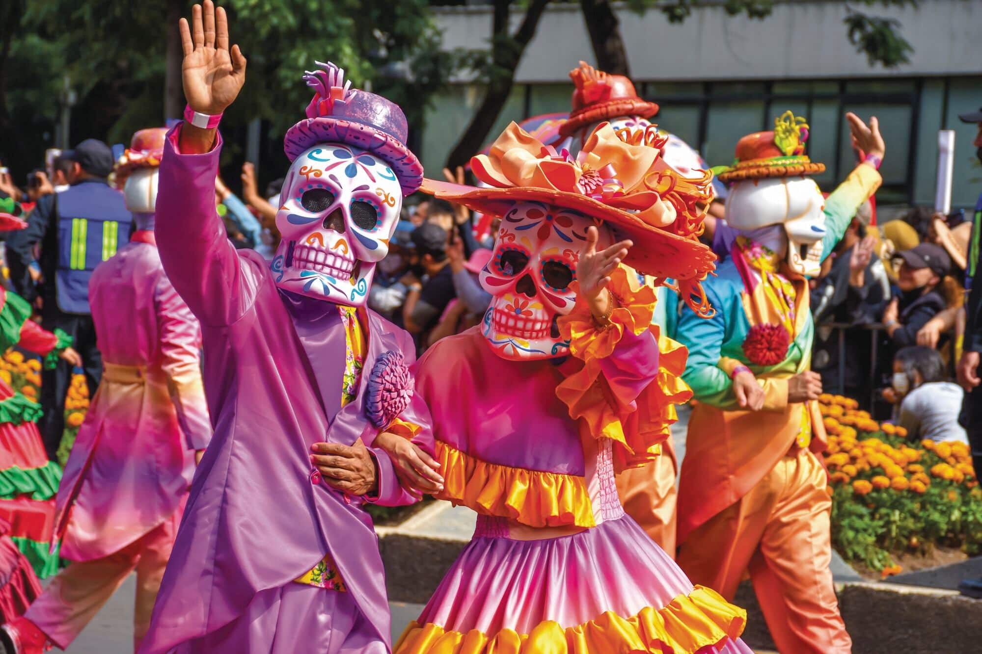 Colourful characters waving from a Day of the Dead parade