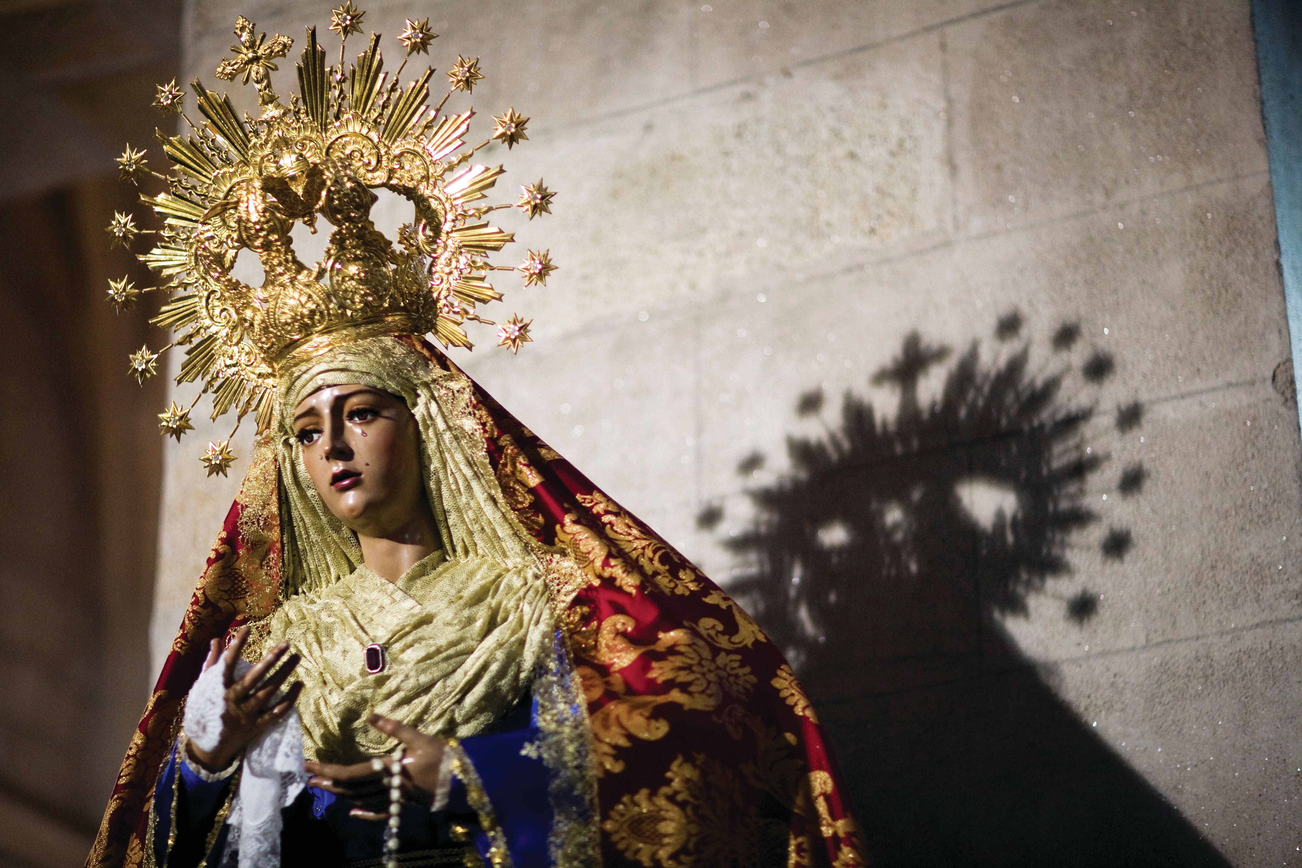 Ornate religious statue of the Virgin Mary wearing a richly embroidered robe and a golden crown adorned with stars.