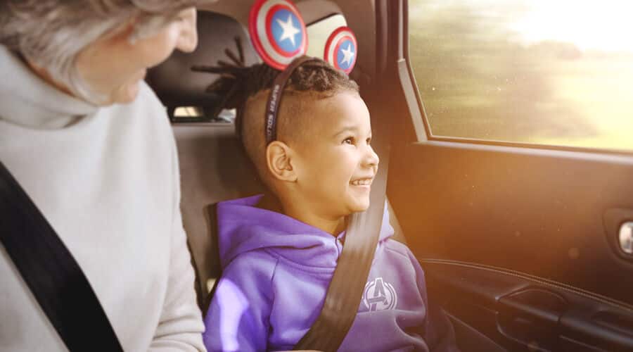 A child wearing Captain America themed Mickey Ears in a car.