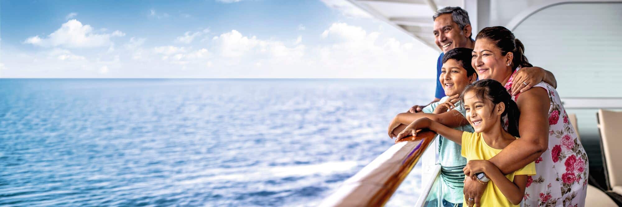 A family of four on a cruise ship looking out to sea.