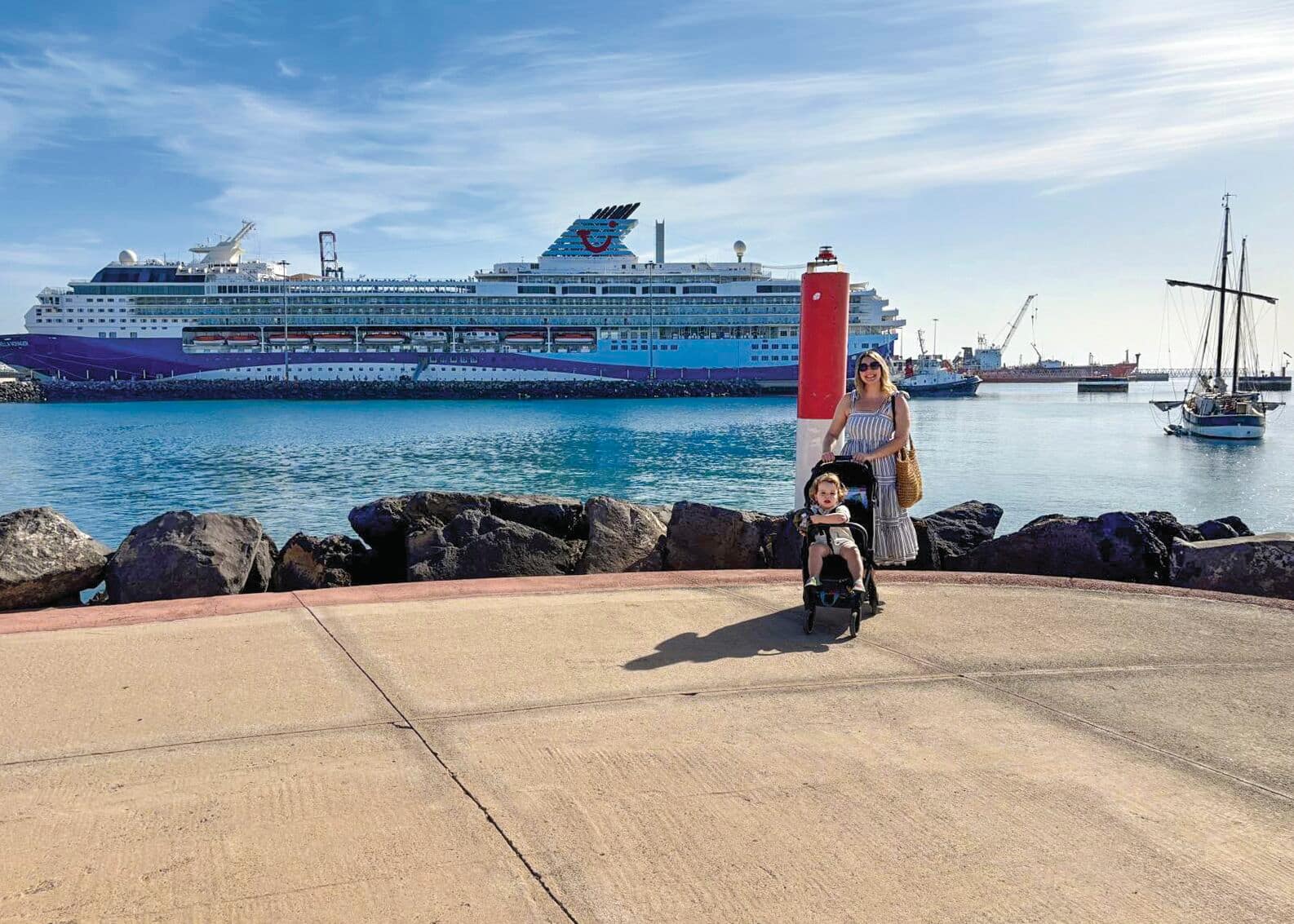 A mother with a buggy in front of a Marella ship.