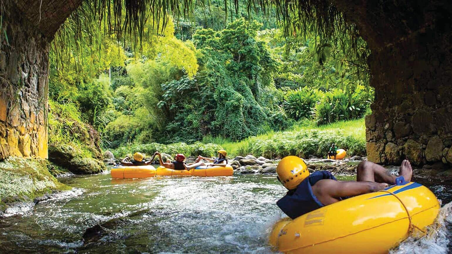 People in bright yellow inflatable tubes floating on a flowing river through a cave opening.