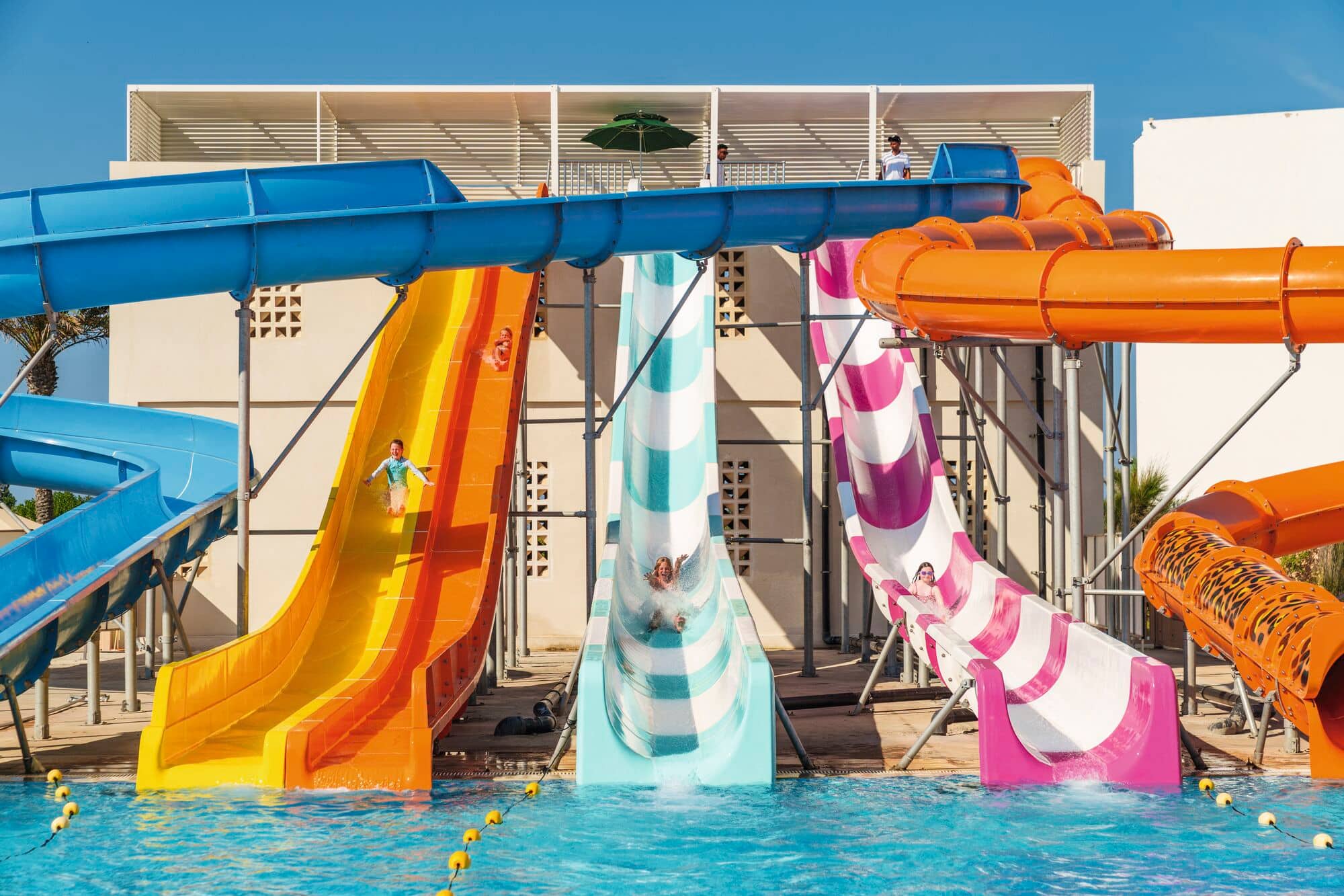 Kids sliding down colourful waterslides.