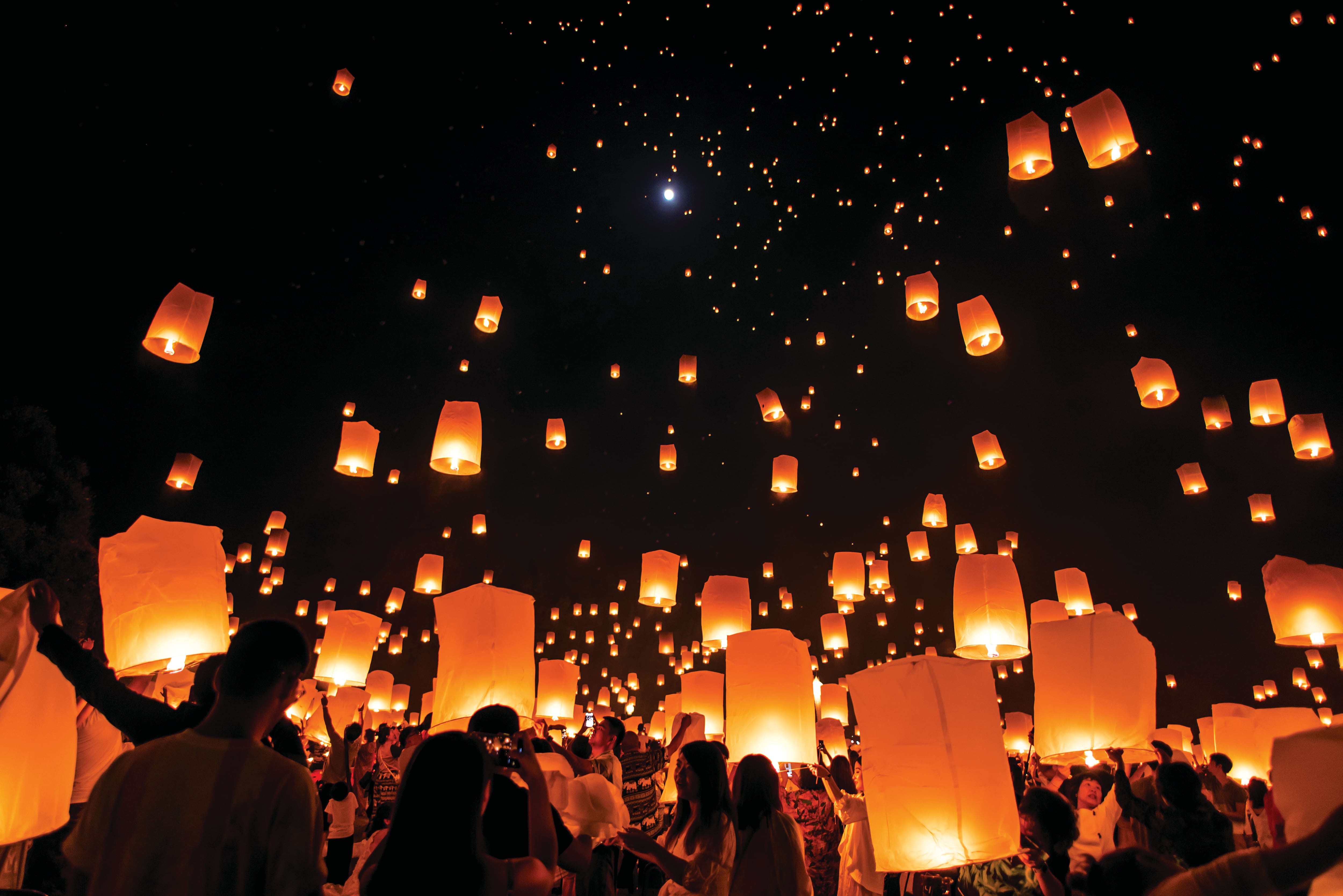 Sky lanterns floating into the night sky during a festival.