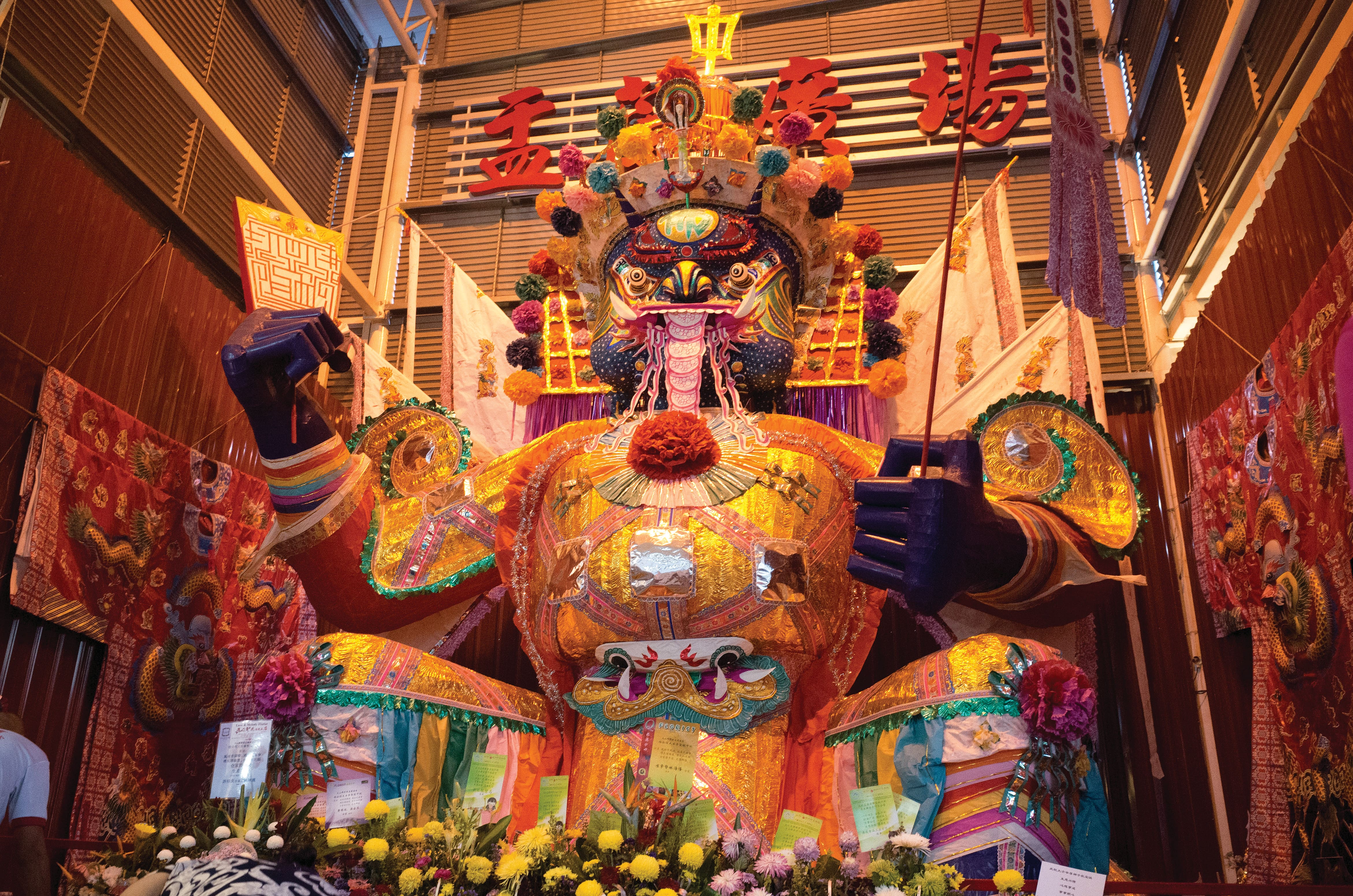Colourful festival sculpture displayed inside a decorated hall.