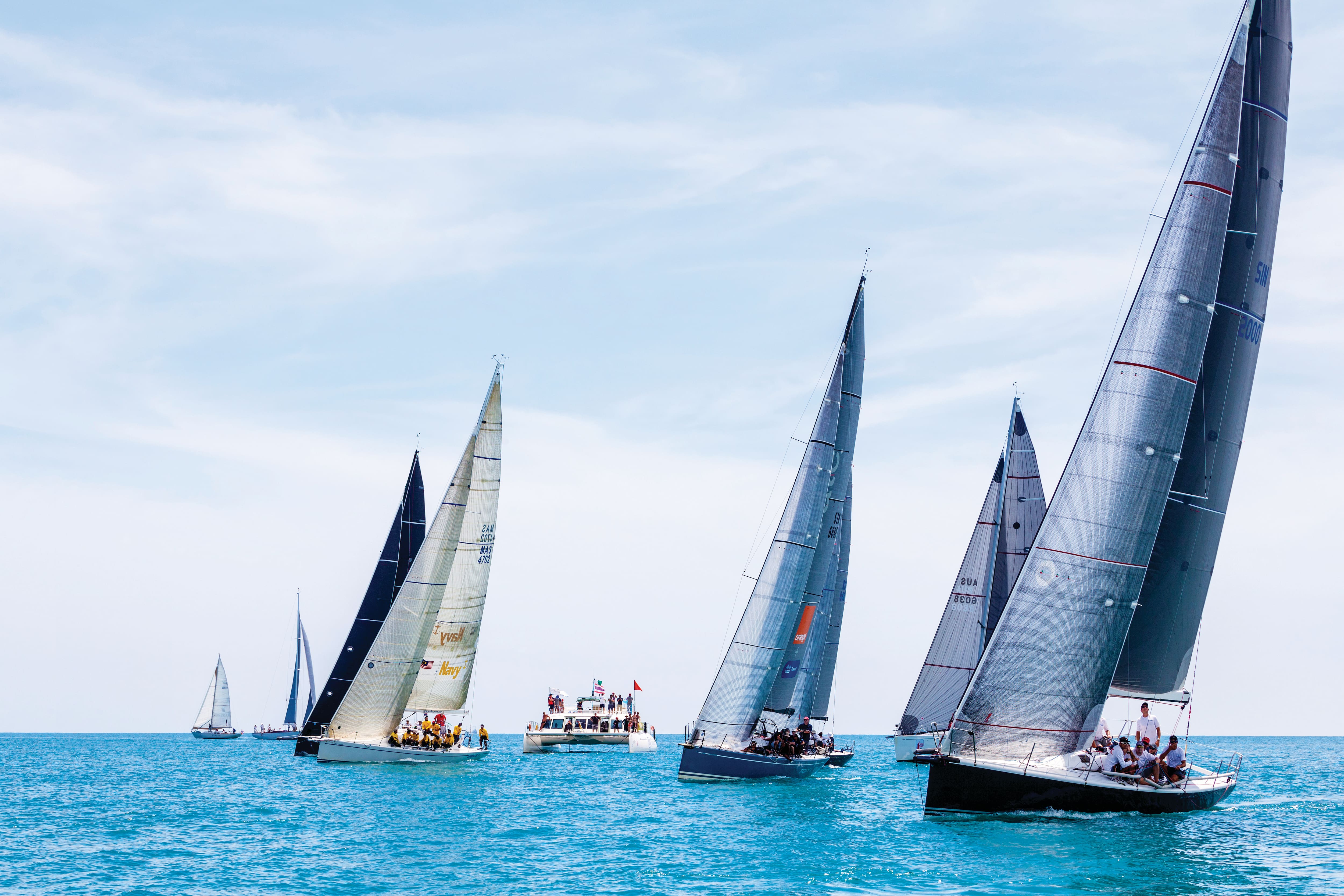 Sailboats racing across the sea on a bright day.