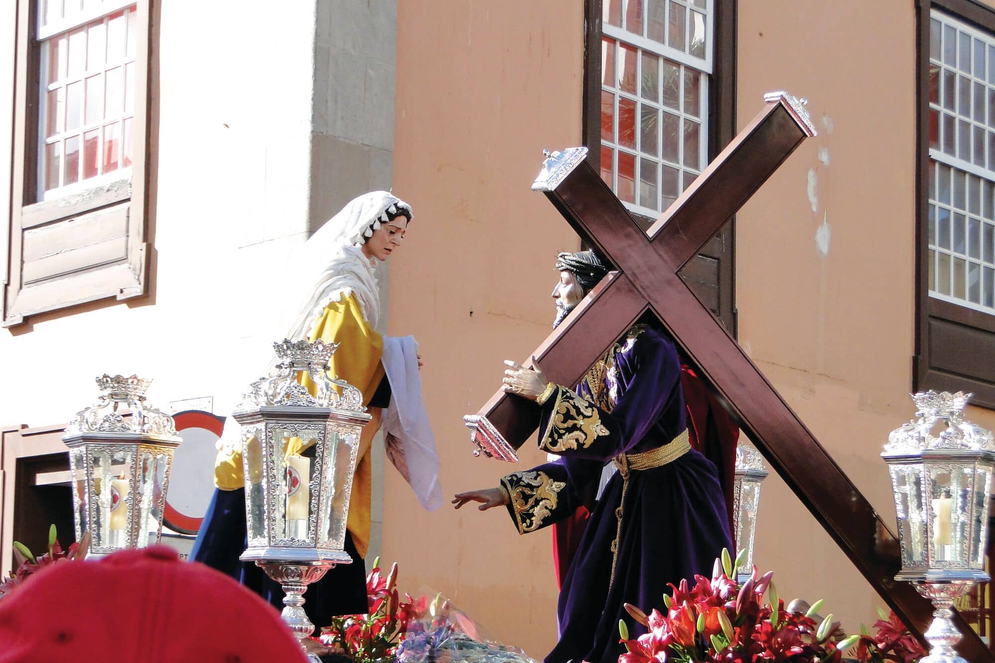 Statue of Jesus carrying a cross and statue of the Virgin Mary being carried through a street procession.