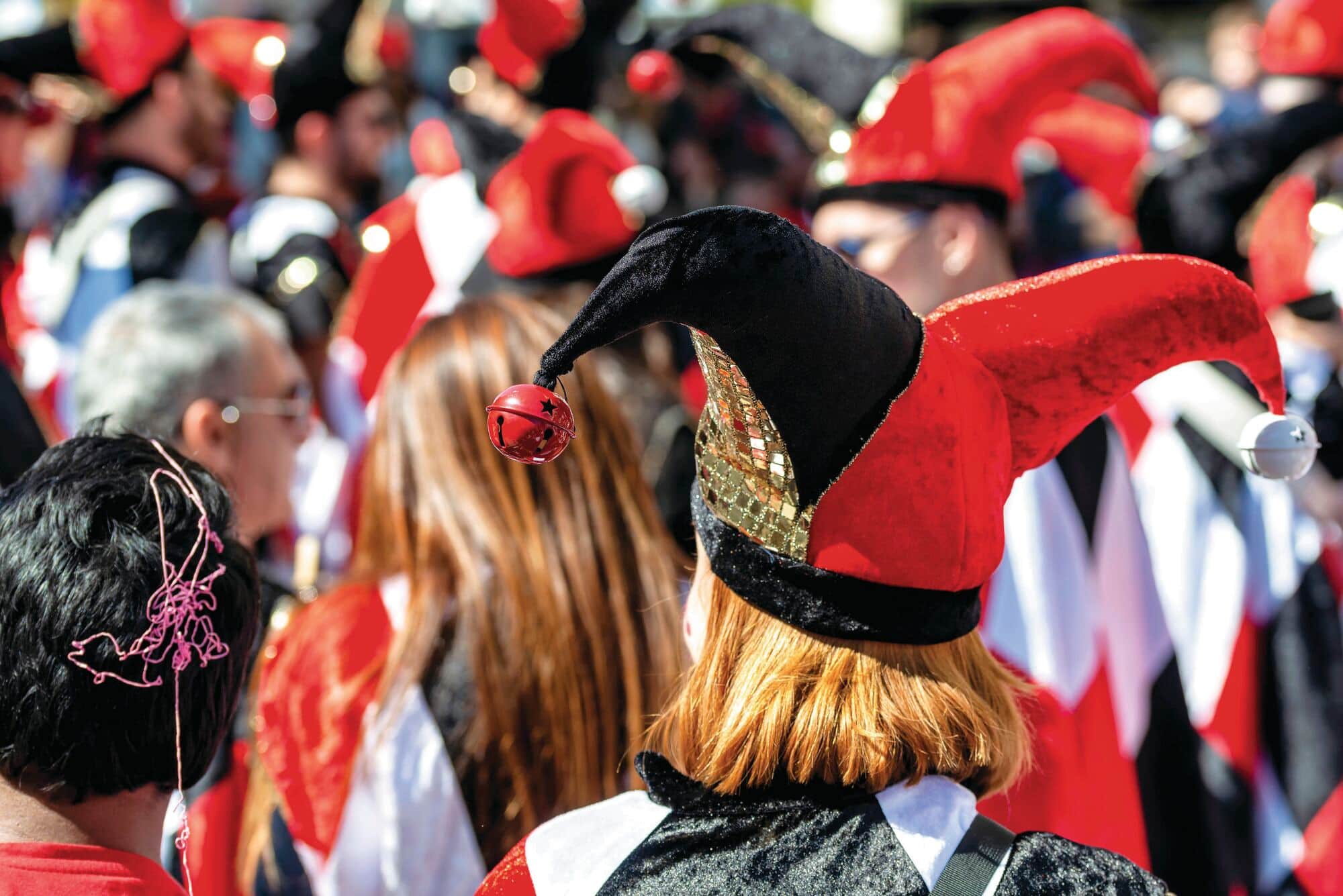 People wearing red and black jester-style hats with bells