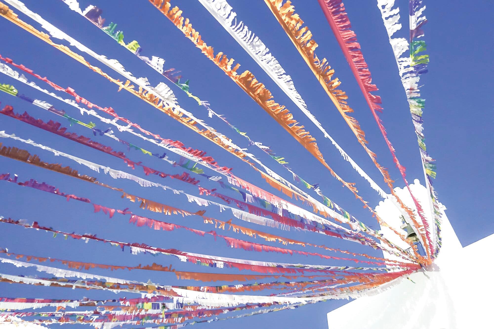 Colourful festival streamers against a blue sky