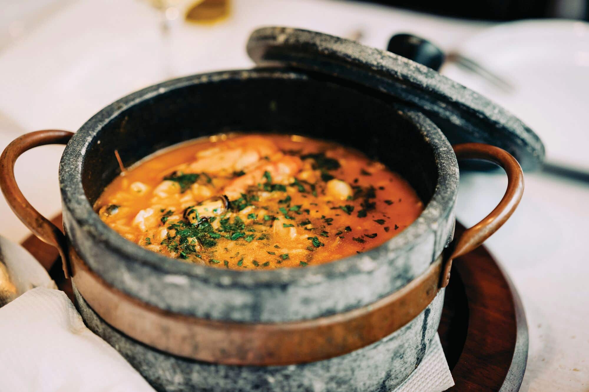 Stew with herbs served in a rustic stone pot.