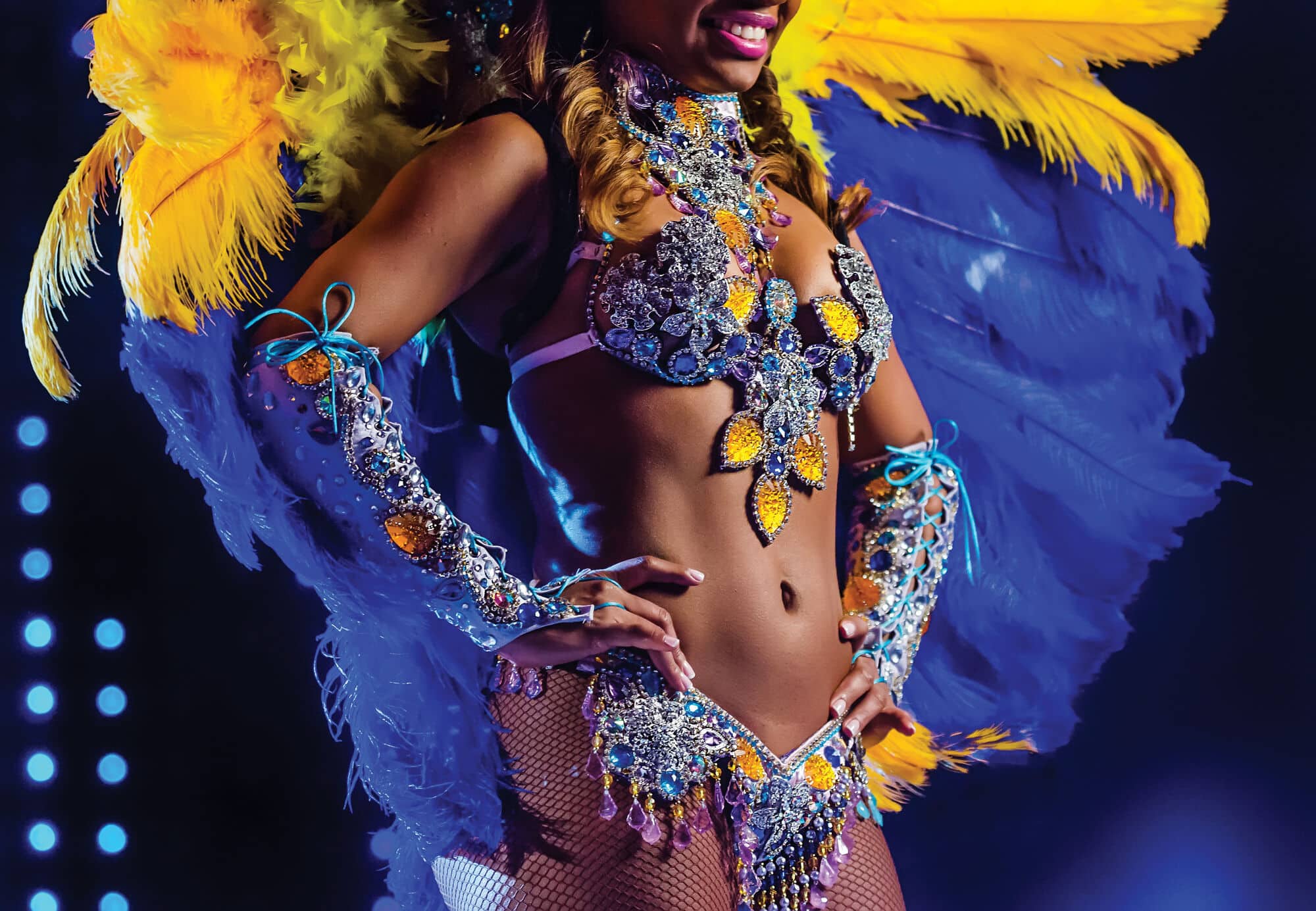 Woman wearing carnival attire in front of a dark backdrop.