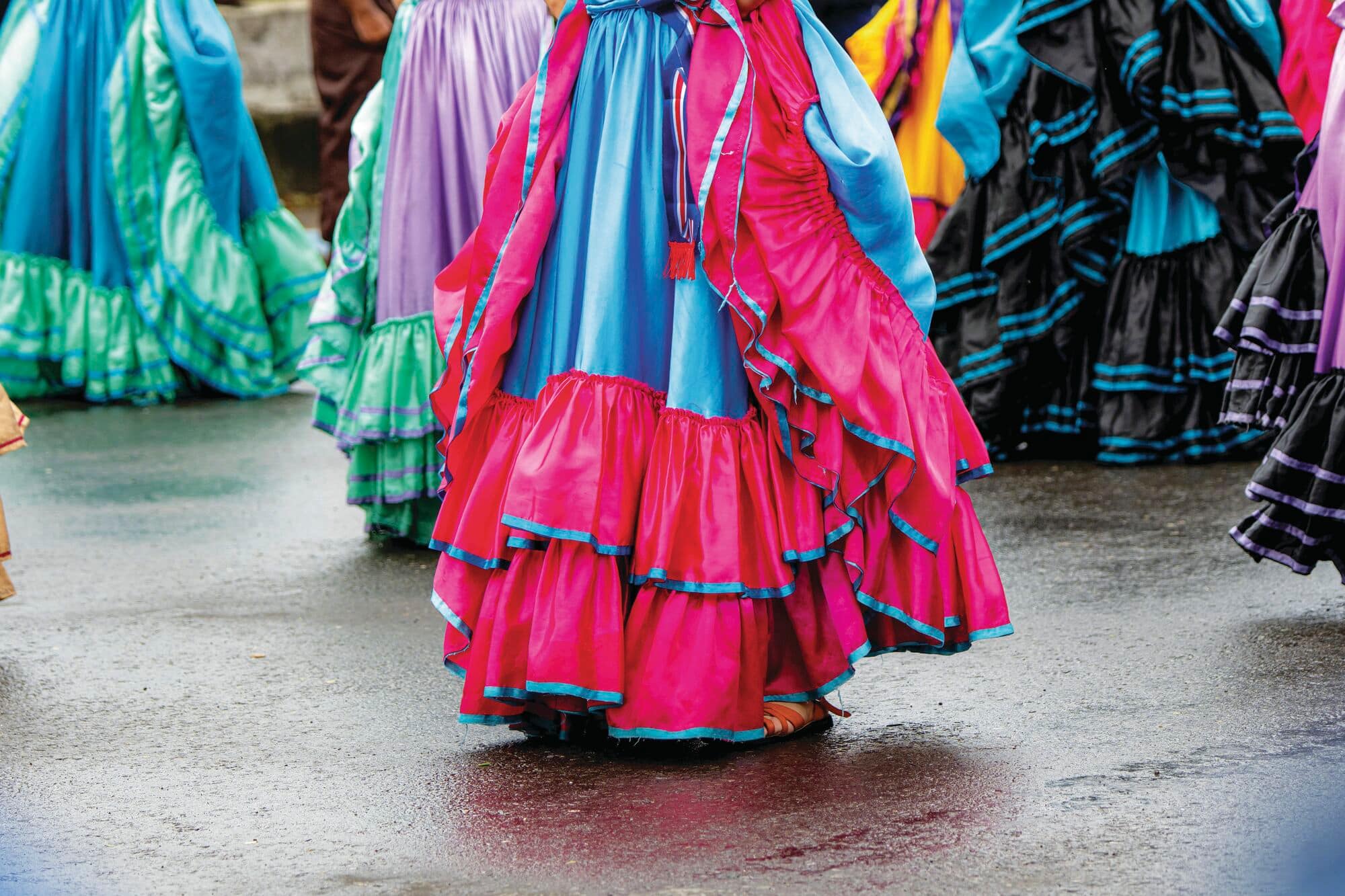 Multi-layered traditional folk dance skirts in bright pink, blue, and green tones