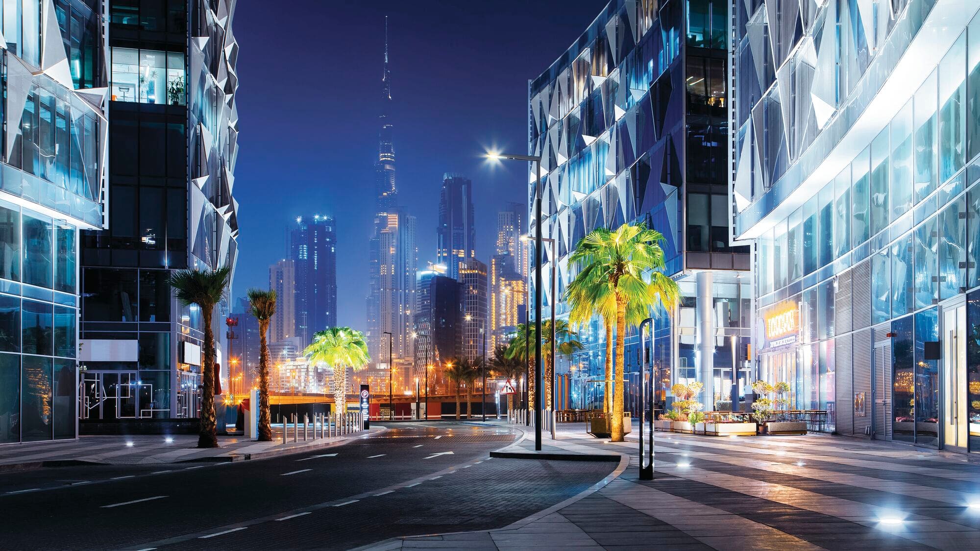 Night view of the Dubai Design District with the Dubai skyline featuring the Burj Khalifa in the distance