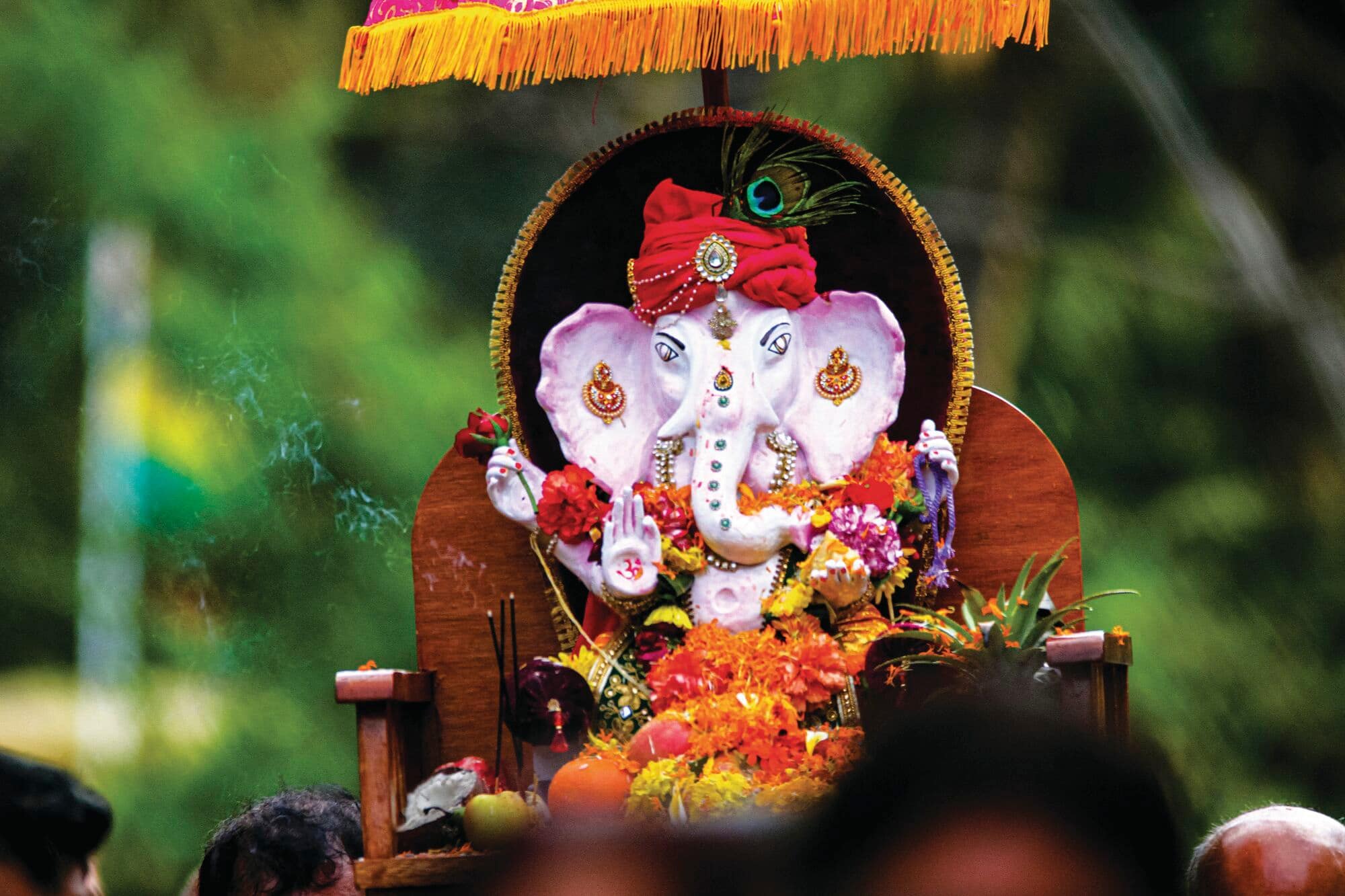 Decorated Ganesha statue adorned with flowers during a religious festival procession.