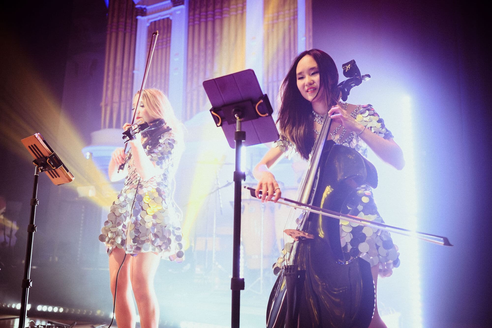 A cellist and violinist performing on stage.