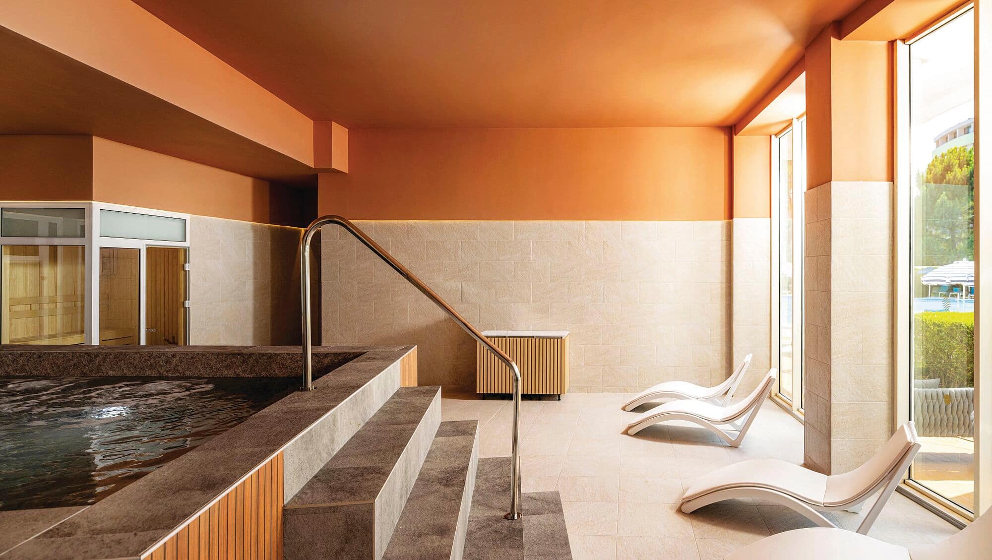 Indoor spa pool with relaxation loungers and floor-to-ceiling windows at The AluaSoul Sunny Beach.